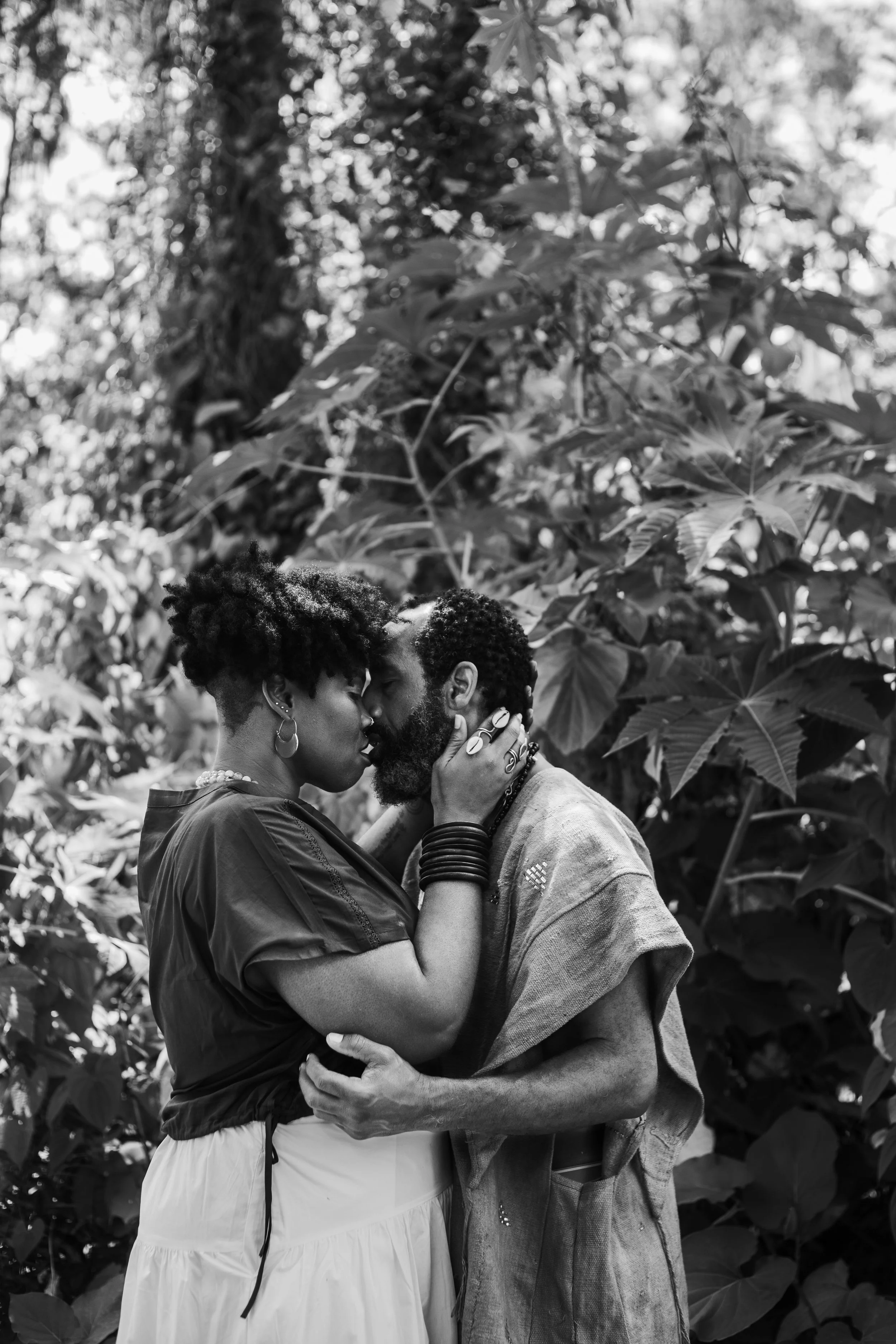 a black couple embraced ready to kiss surrounded by a tropical wooded forest