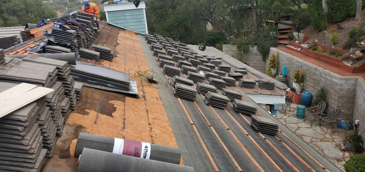 A modern building on a grassy hill with snow-capped mountains in the background.