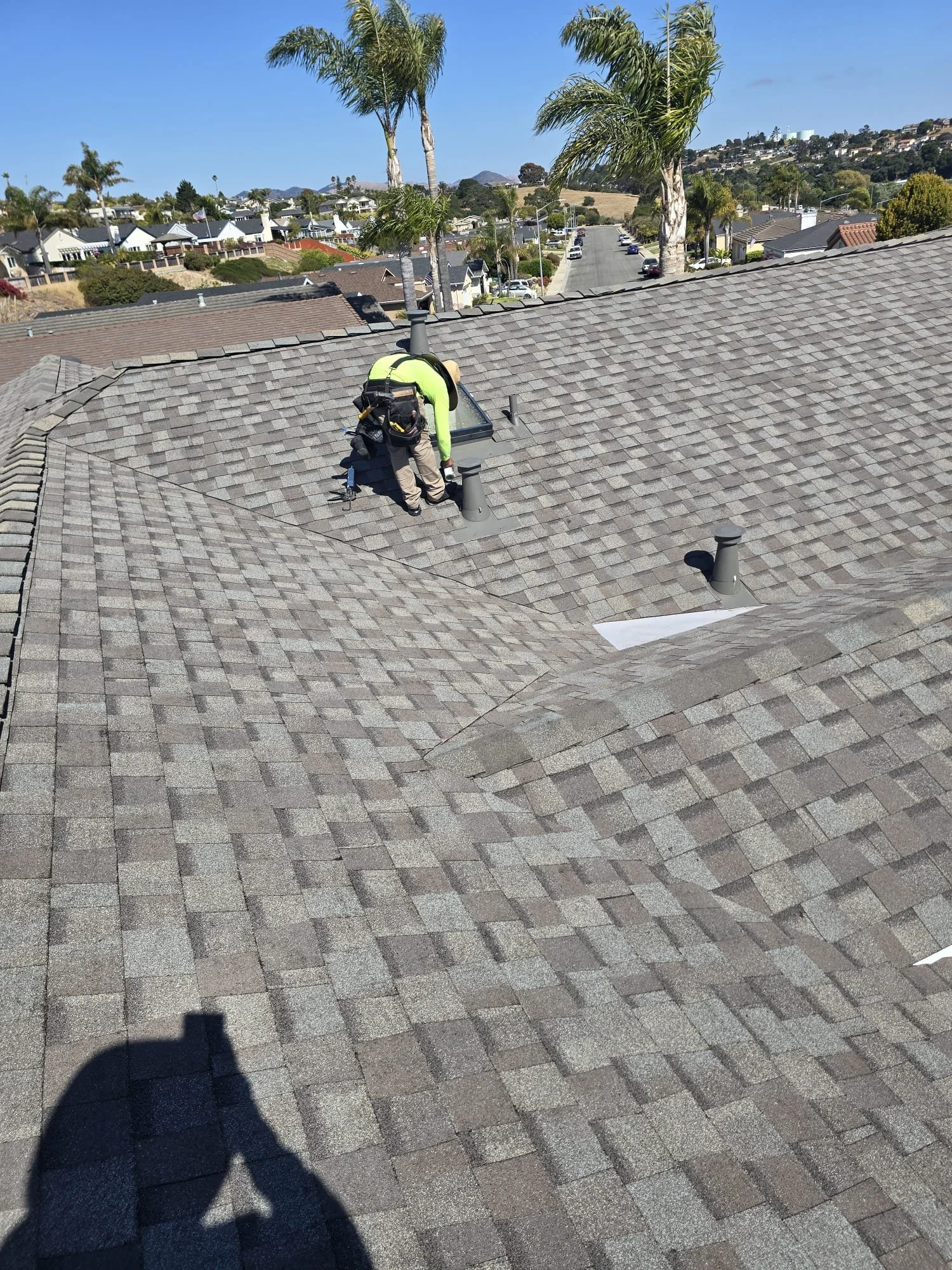 Scenic landscape with a turquoise lake, green hills, and mountain range under cloudy sky.