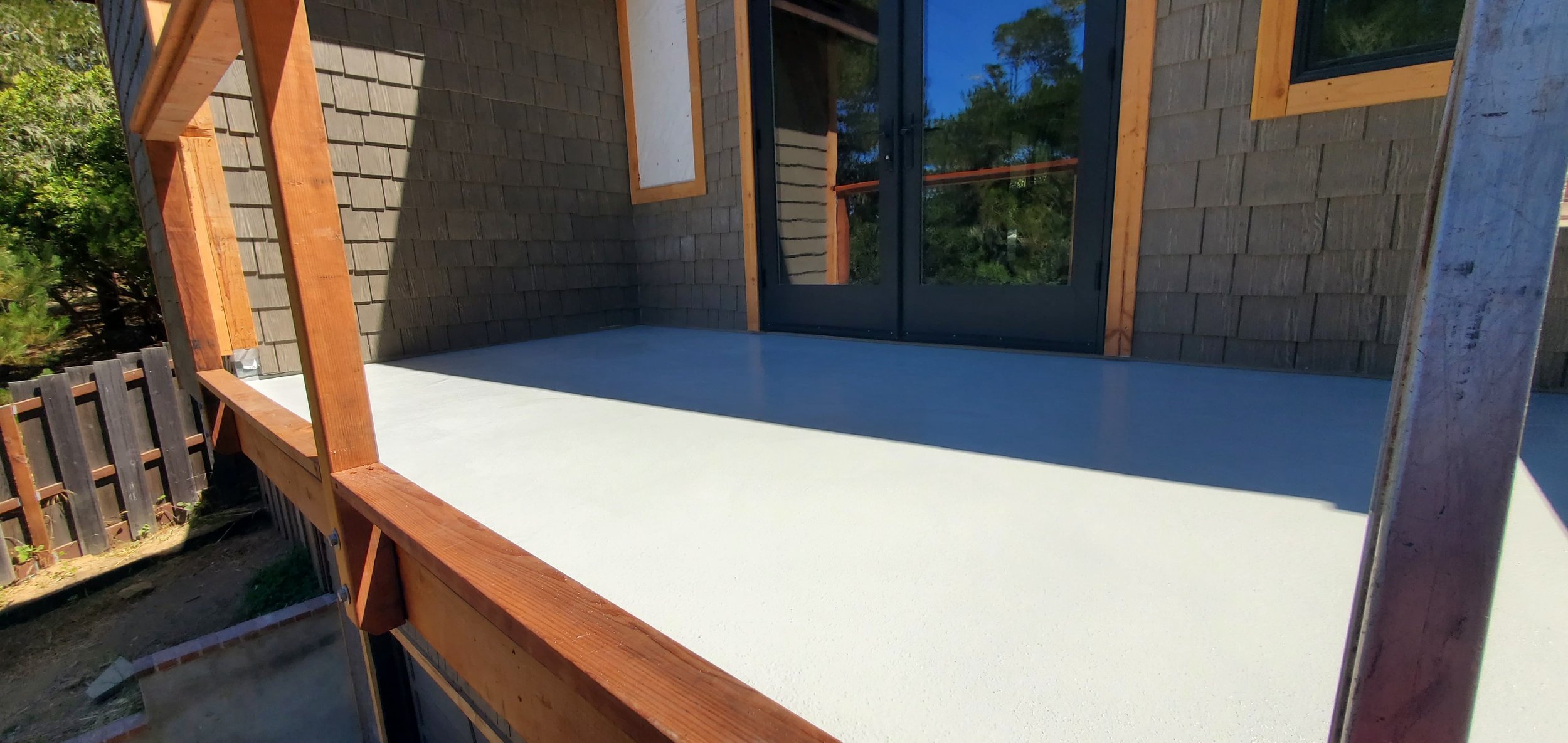 A scenic landscape with a large body of turquoise water, rolling green hills, and rugged mountains in the background under a cloudy sky.