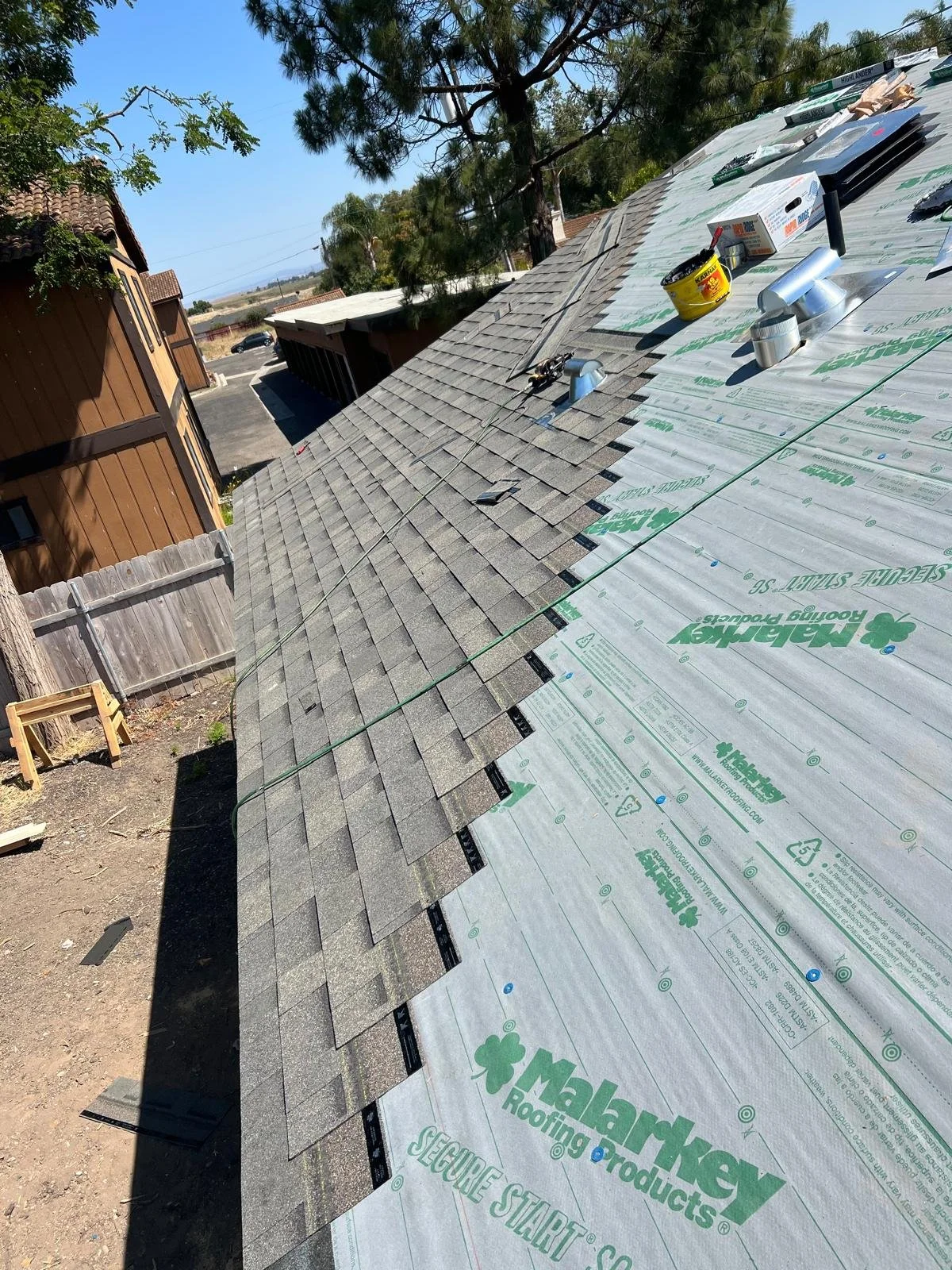 Modern wooden building with large glass window set in a mountainous landscape with dry grass and sparse trees.
