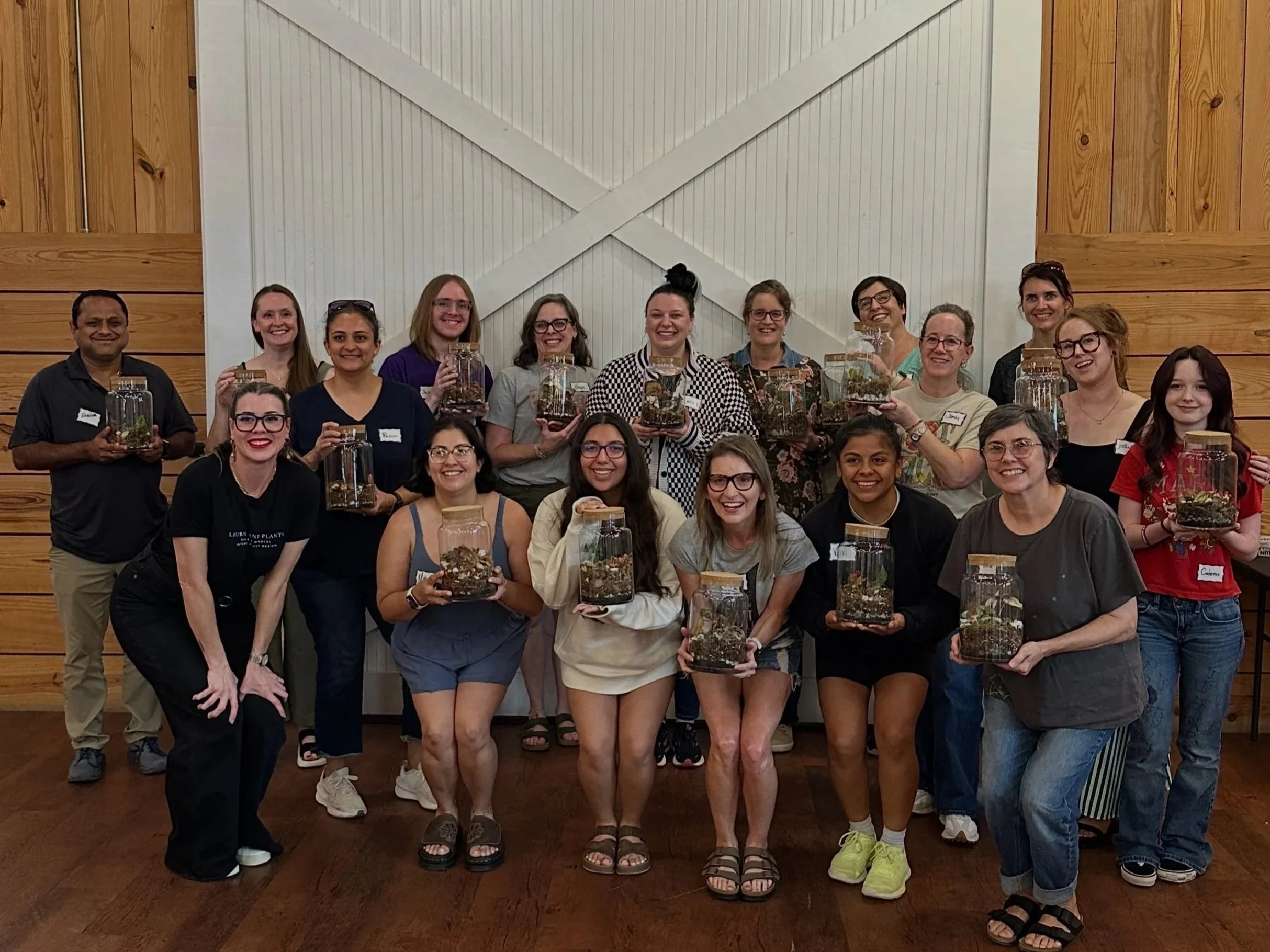 Participants proudly display their finished terrariums during a community plant workshop hosted by Lauren and Plants in Fort Worth, Texas.