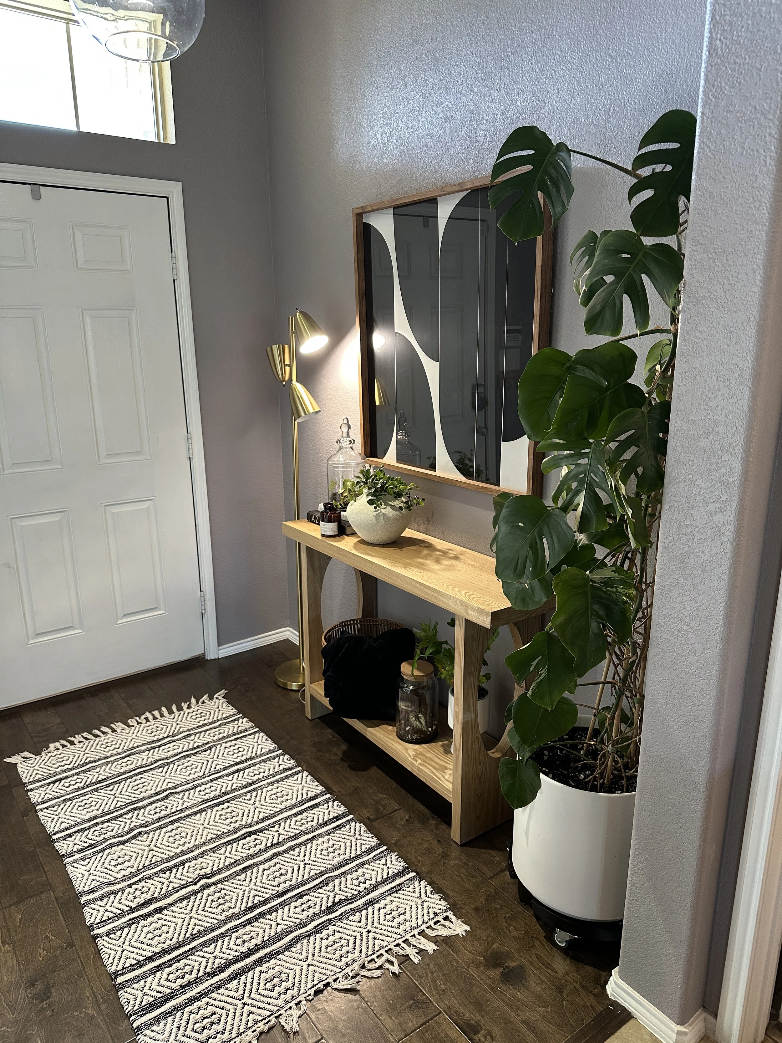 Thoughtfully styled entryway featuring a climbing monstera, warm wood tones, and intentional indoor plant placement that creates balance, softness, and visual flow within the home.