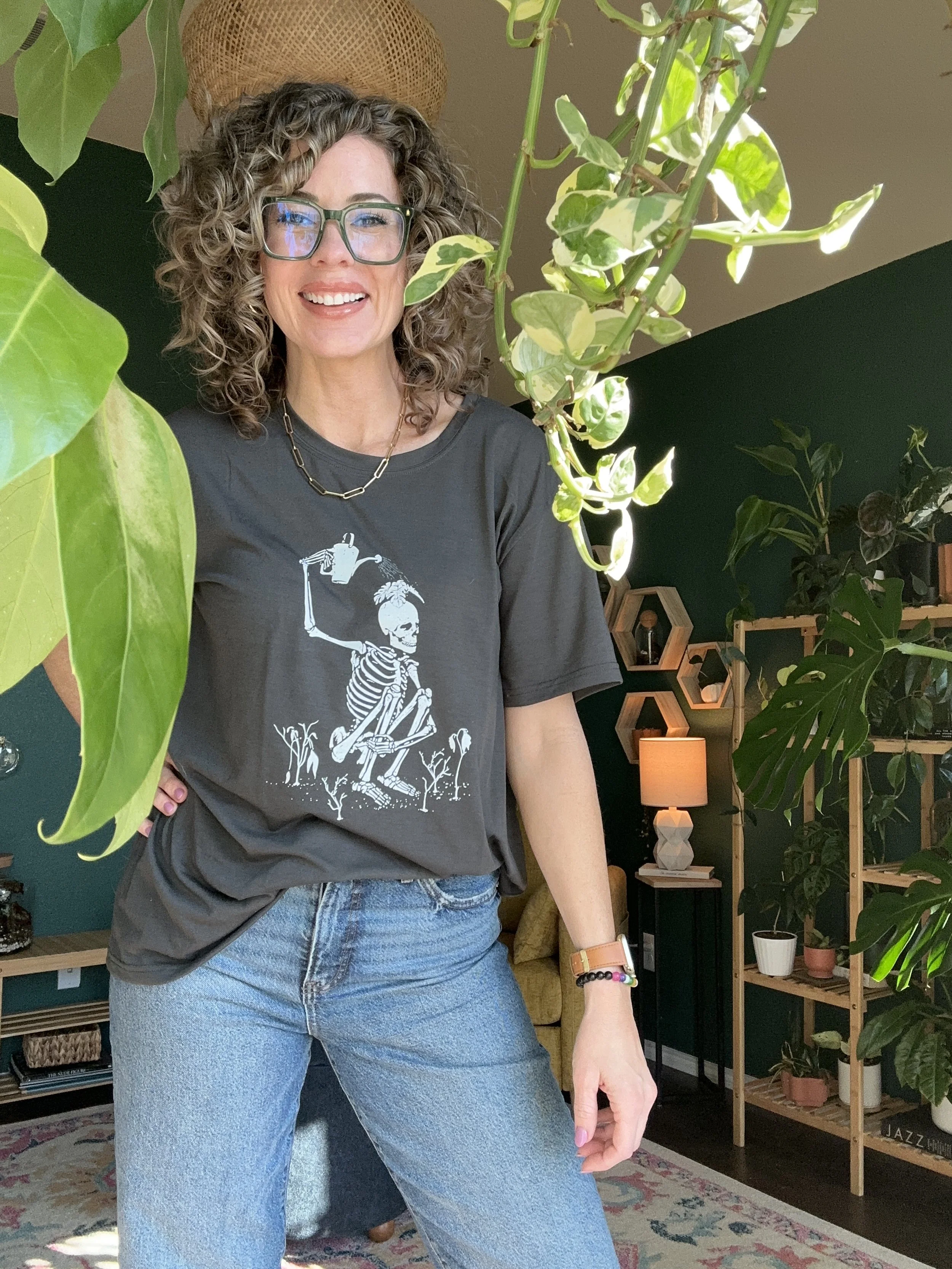 Lauren White, owner of Lauren and Plants, standing in her plant filled studio surrounded by styled indoor greenery. She offers plant styling, staging, and interior plant design throughout the Dallas Fort Worth area.