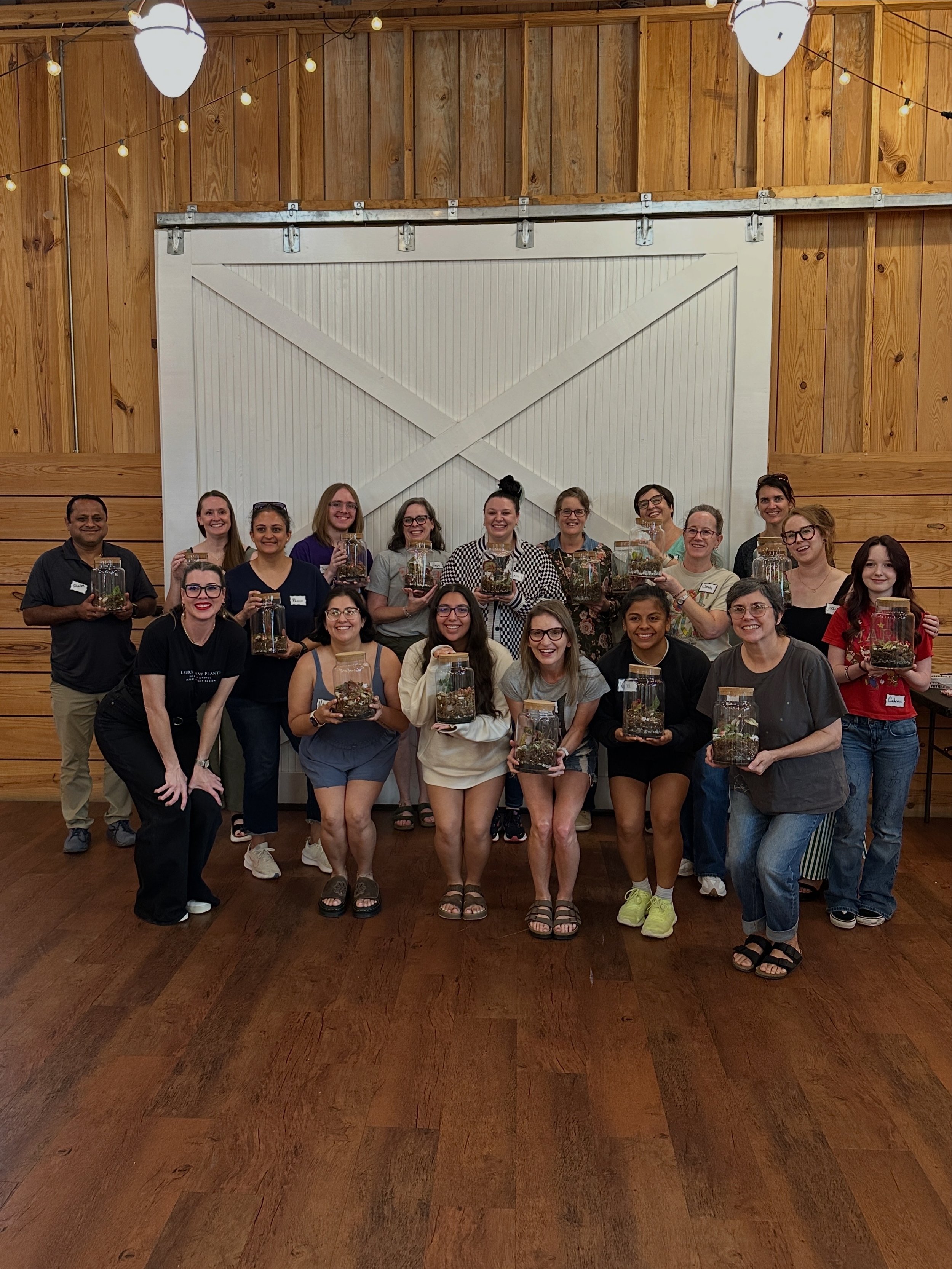 Participants proudly display their completed terrarium creations during a community plant workshop hosted by Lauren and Plants in partnership with Play Frisco.