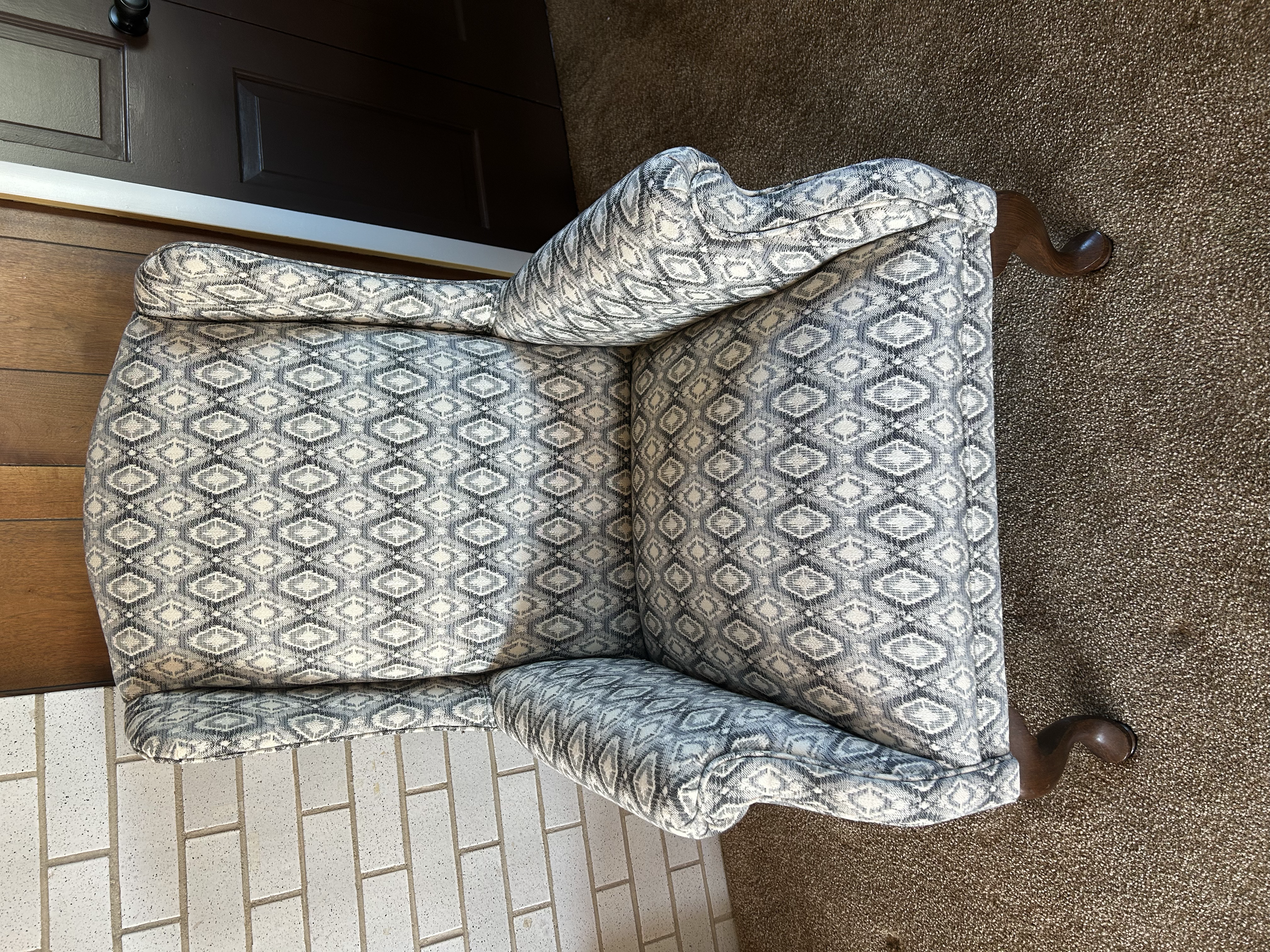 After reupholstery: Vintage wingback chair refreshed in blue and cream patterned fabric, complementing its classic shape and curved wooden legs.