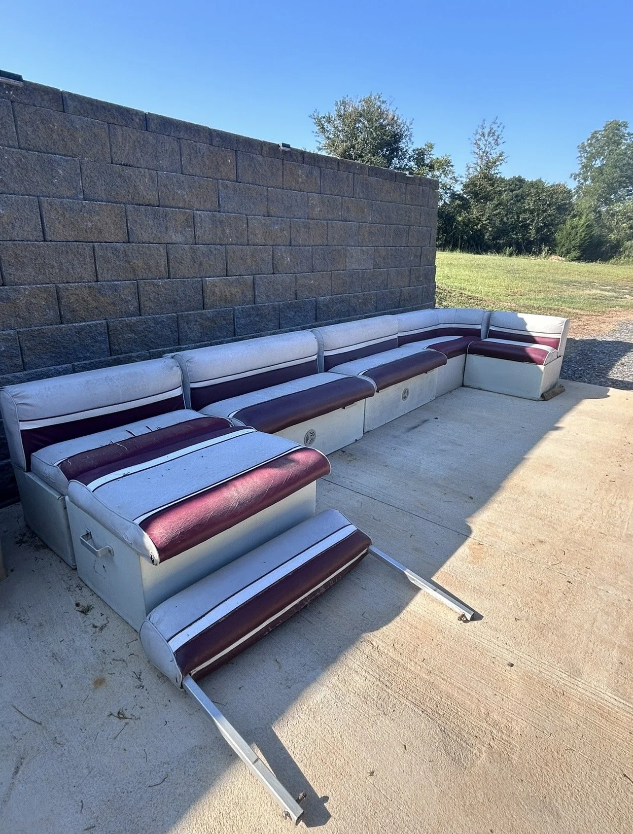 Before boat reupholstery: Boat seating with worn white and burgundy upholstery, ready for an updated look.