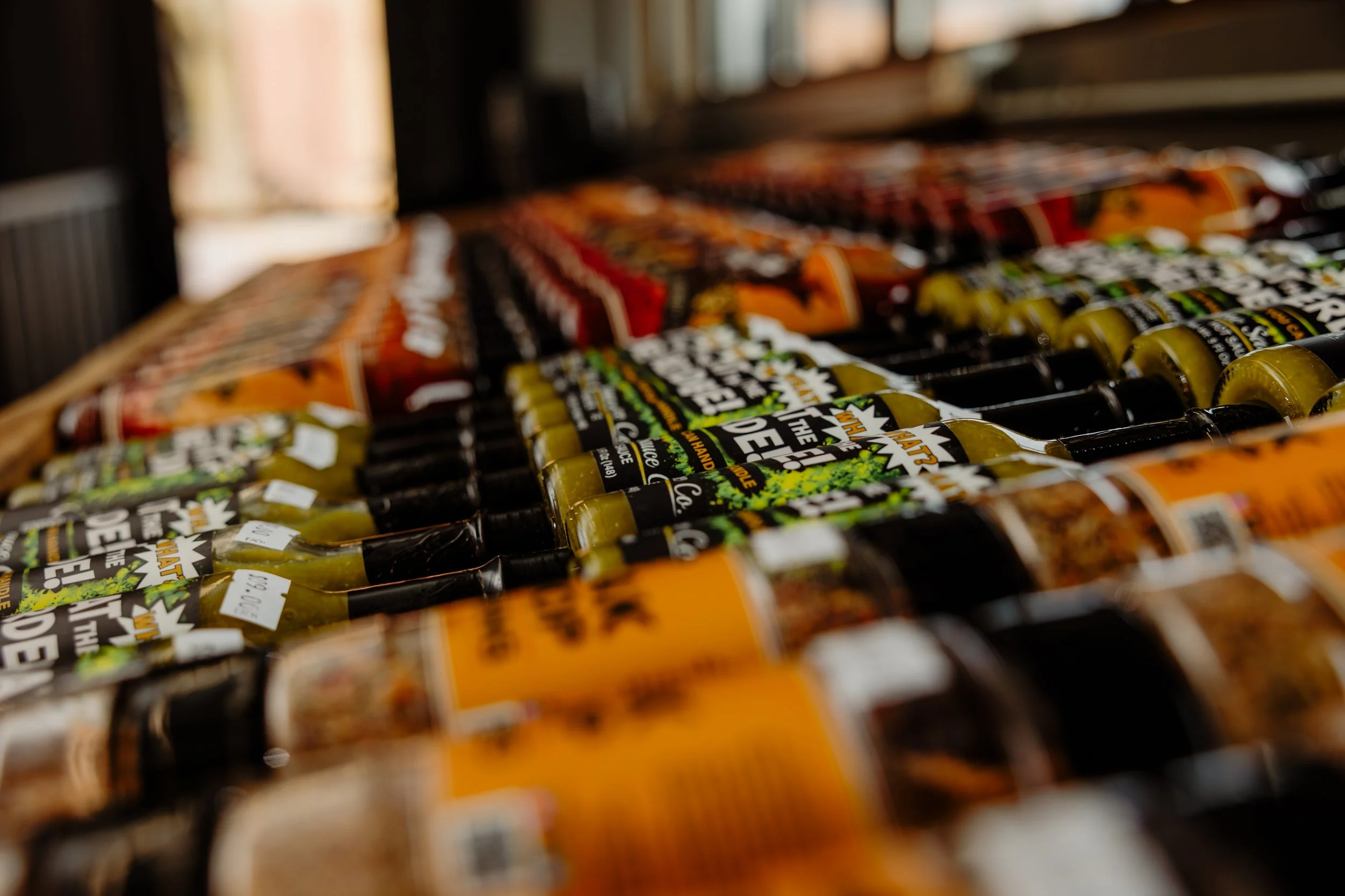 Rows of craft beer bottles with colorful labels on a wooden surface.