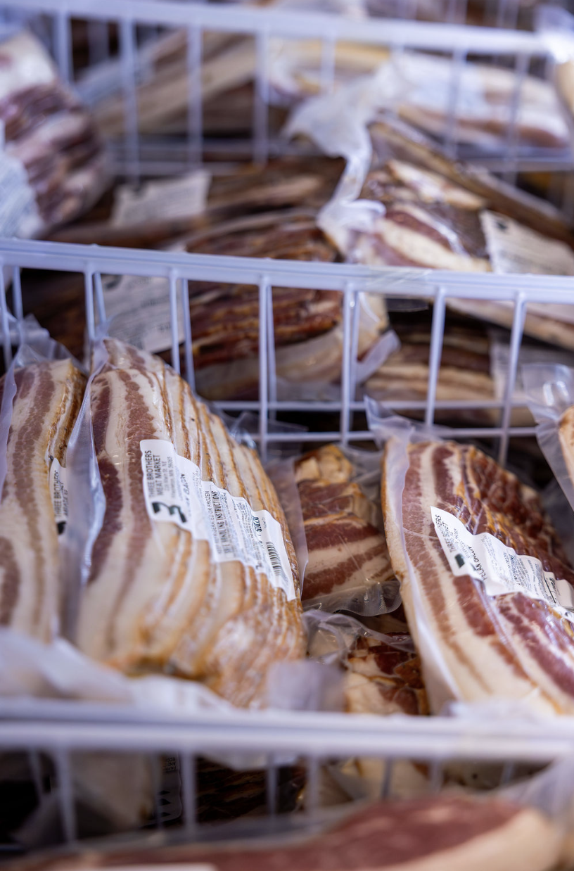 Frozen packs of bacon in a grocery store freezer.