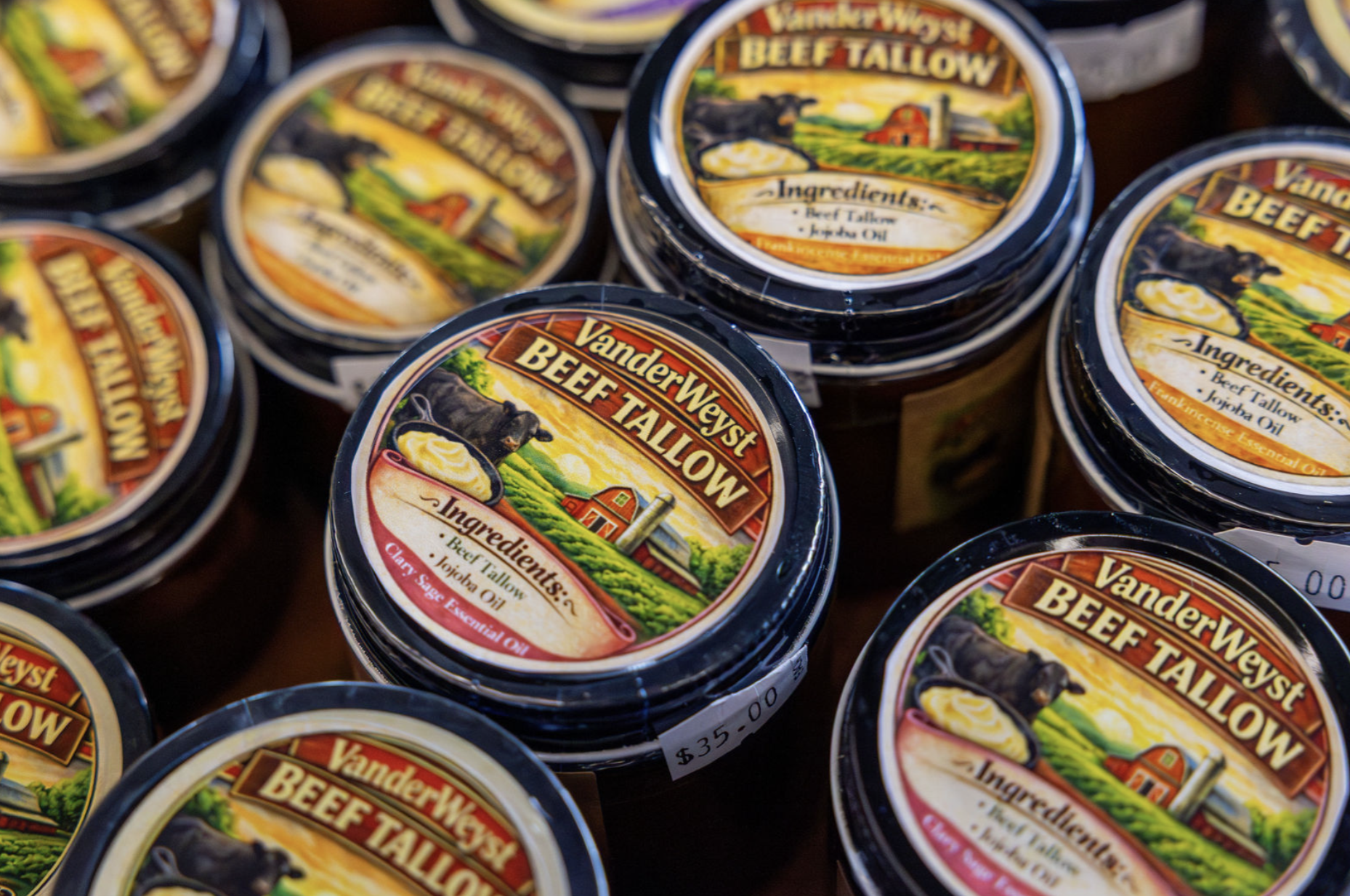 Multiple jars of VanderWyst Beef Tallow with a label showing a farm scene, black cow, and ingredients list including beef tallow and oils.