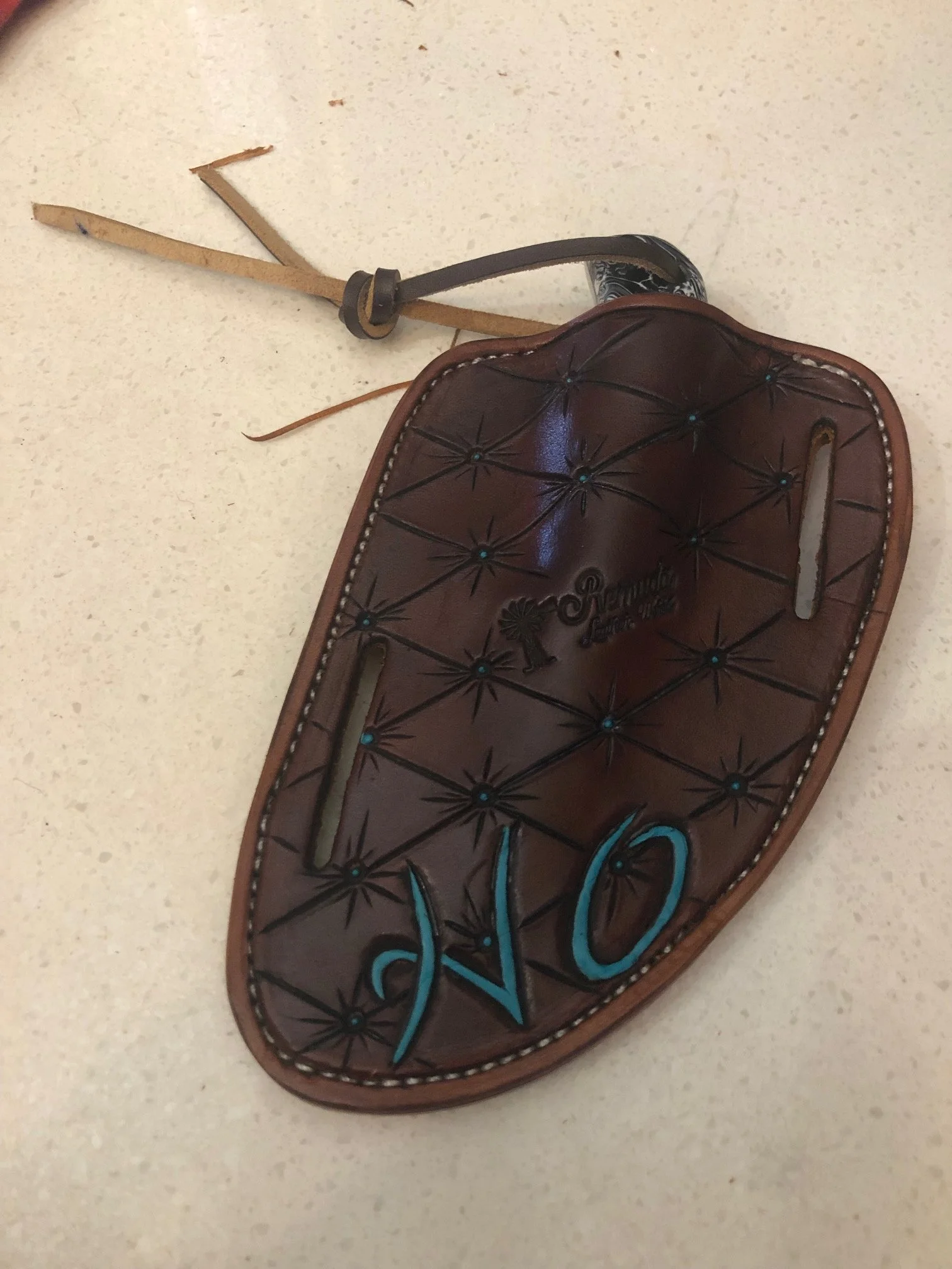 A brown leather knife sheath with hand-painted blue and black details