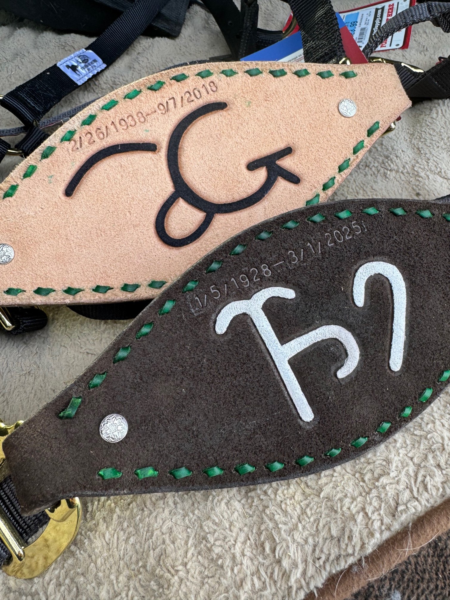 Two leather keychains, one light tan and one dark brown, with hand-stitched border and embroidered letters 'CK' and numbers indicating birth dates.