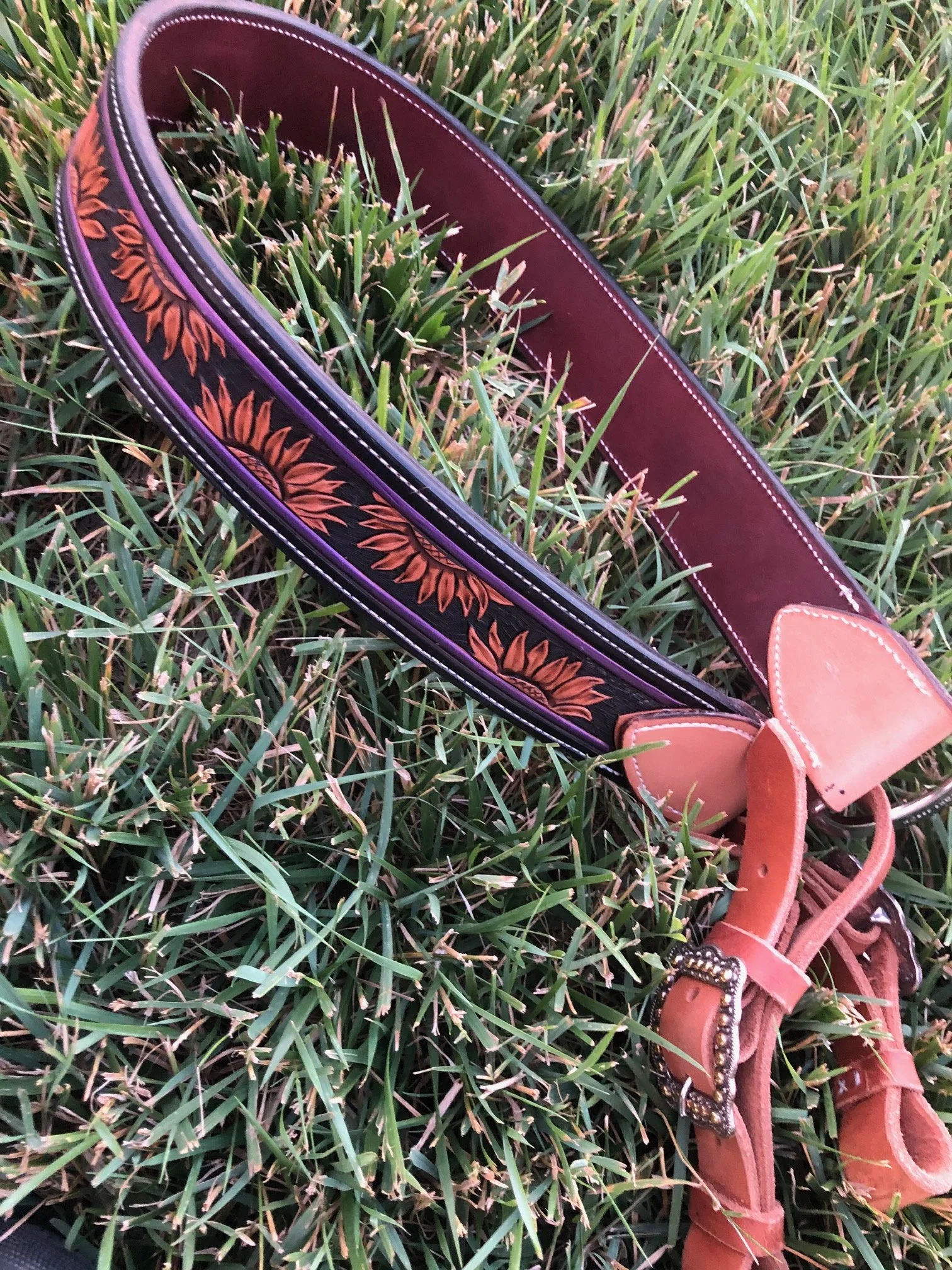A  tripping collarwith sunflower designs rests on green grass.