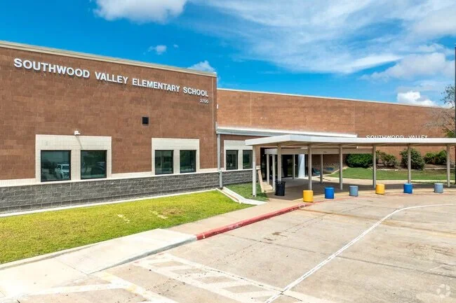 Exterior view of Southwood Valley Elementary School with a brick facade, entryway, and a parking lot with painted markings.