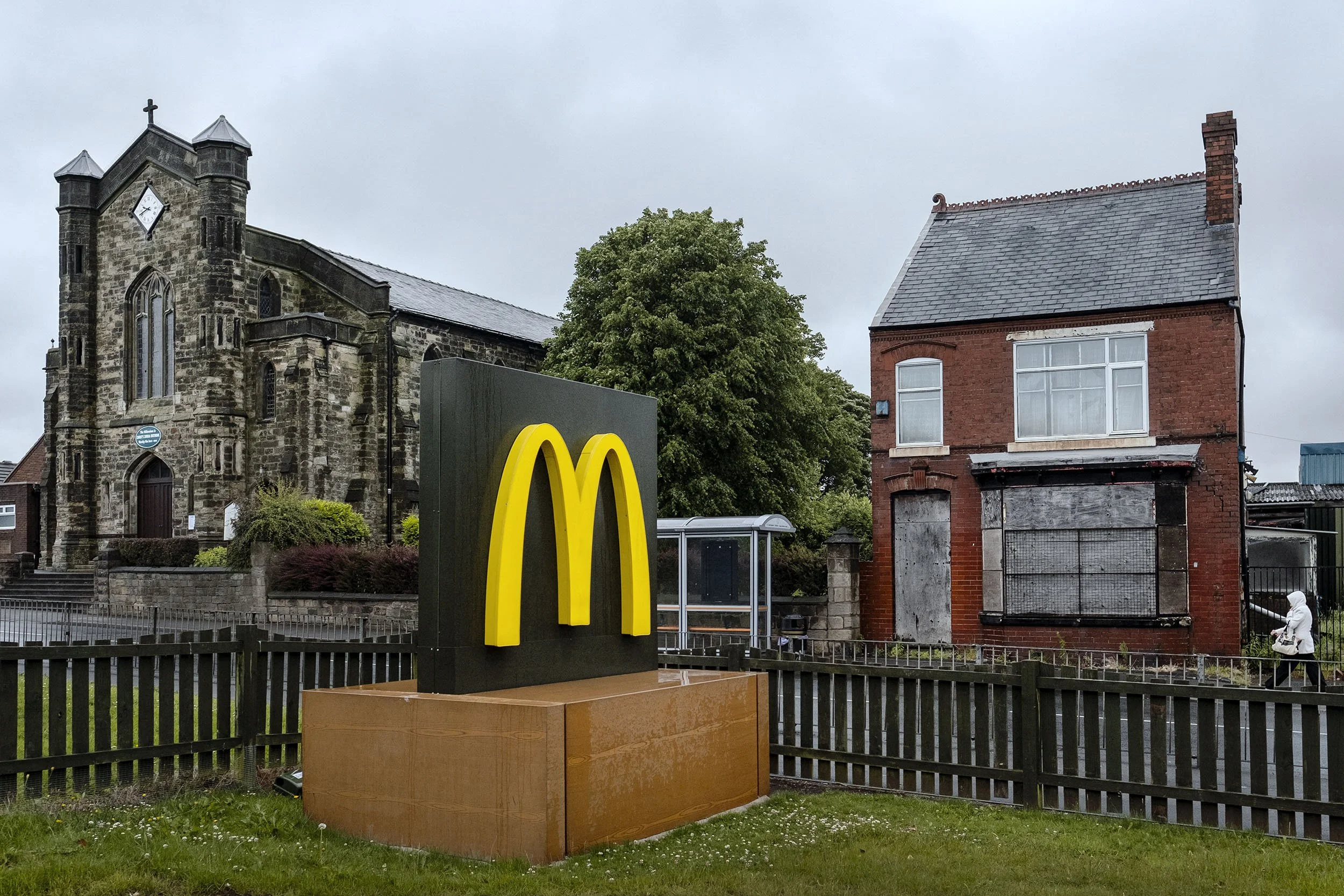 A boarded up house and a church behind a McDonalds sign in Dudley, England.