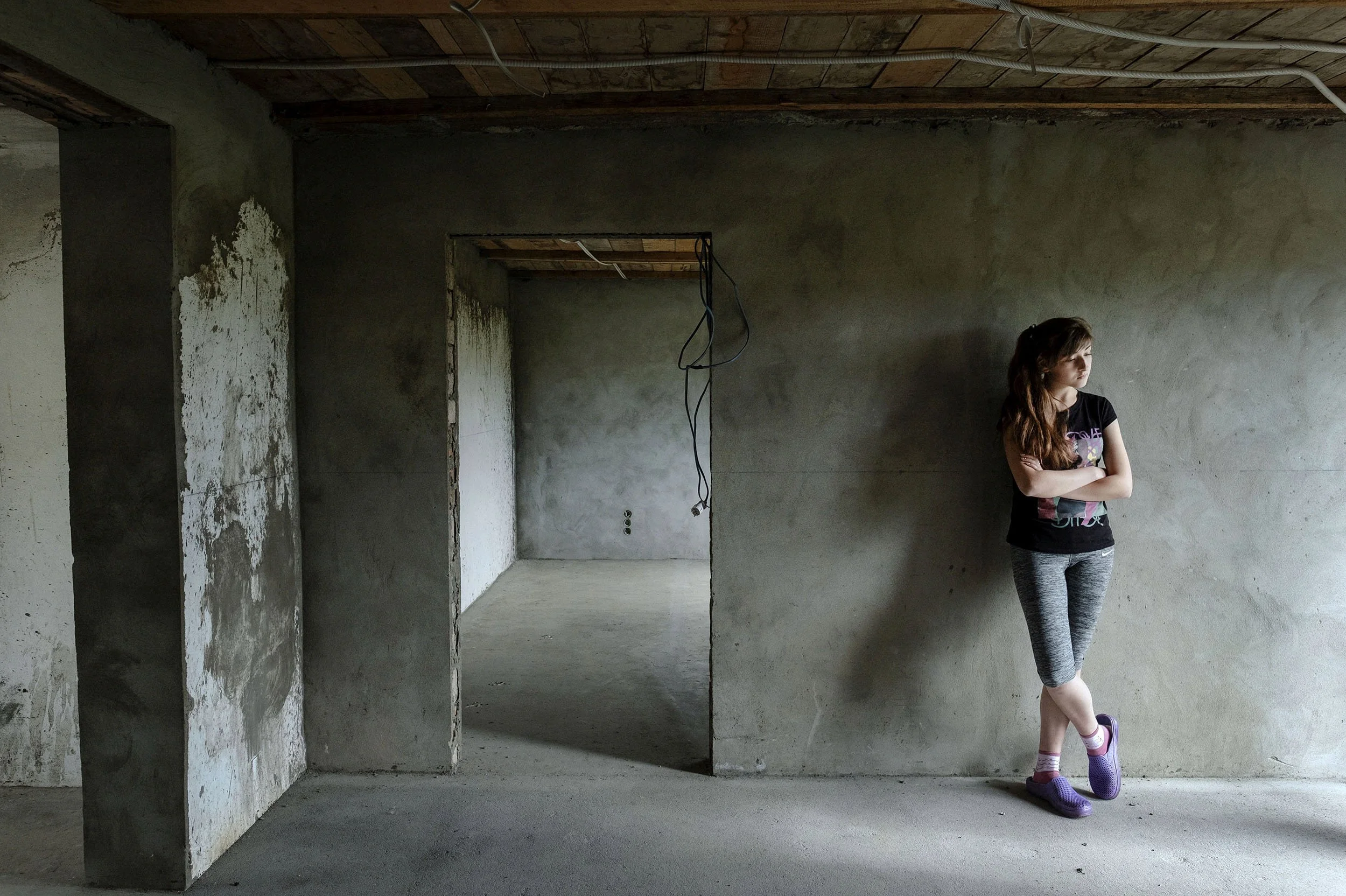 A girl waits for her mother, who has been working in Southern Italy for years, in the house they building but still haven’t completed due to a lack of money. Bobivtsi, Ukraine.