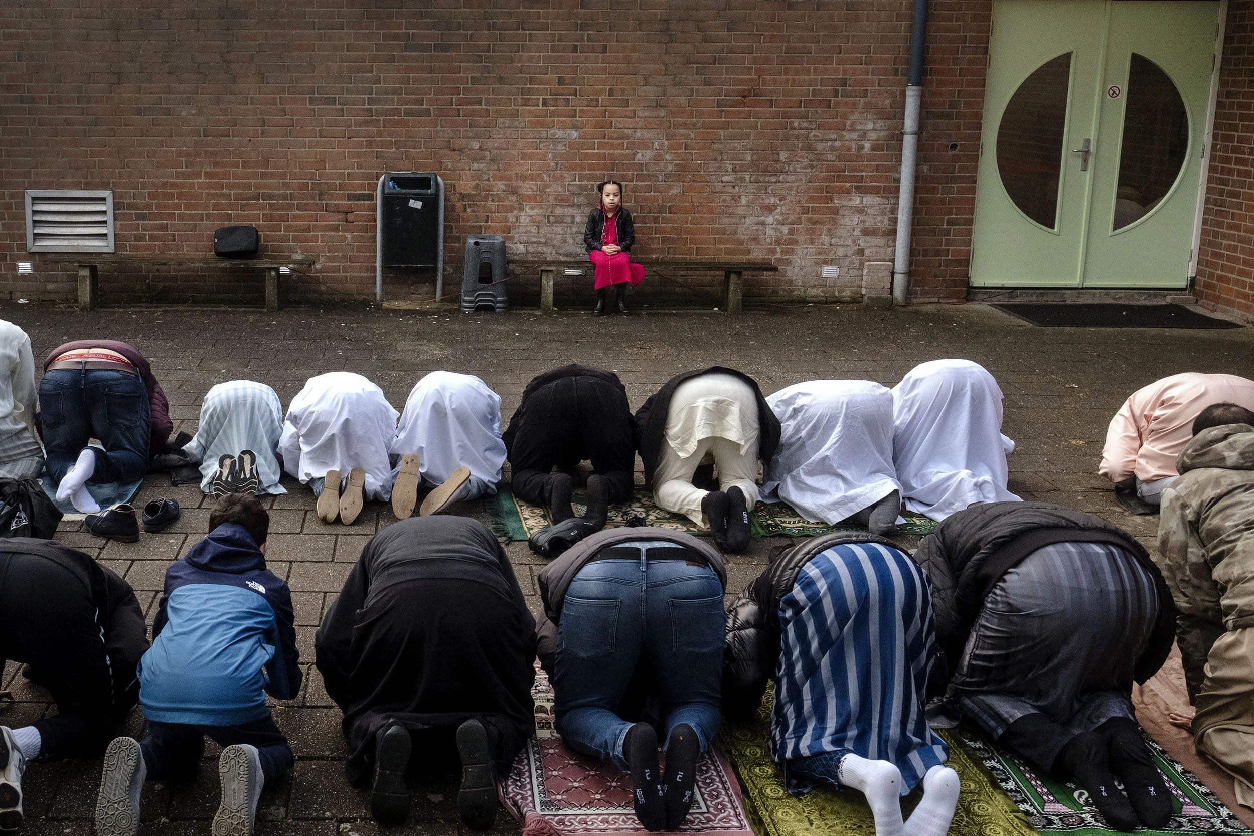A girl watches the men during morning prayer in the Nour al Houda Mosque. Muslims celebrate Eid al-Fitr. Arnhem, the Netherlands.