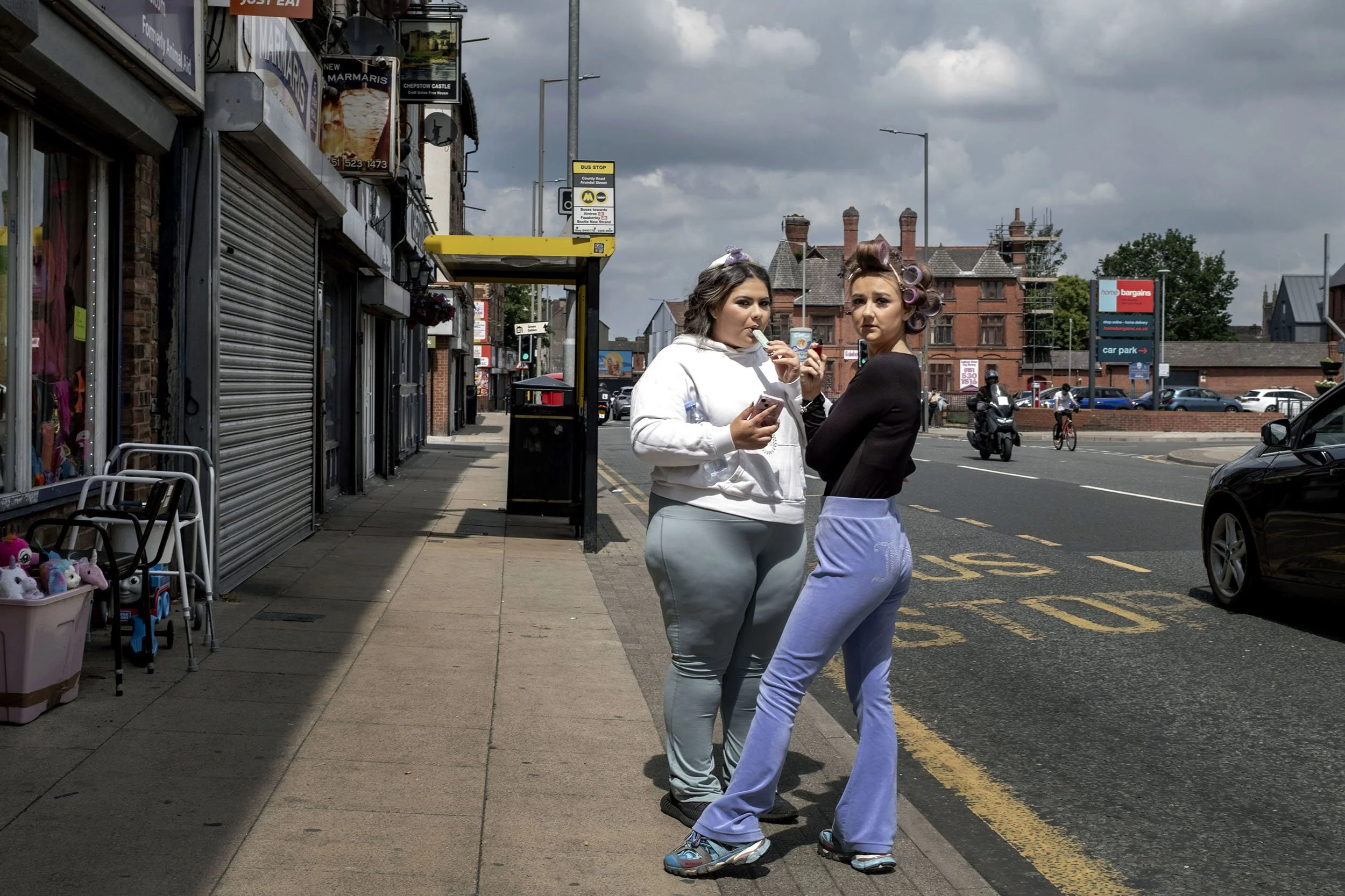 Two woman take a smoke break outside the hairdresser’s, Liverpool, UK.