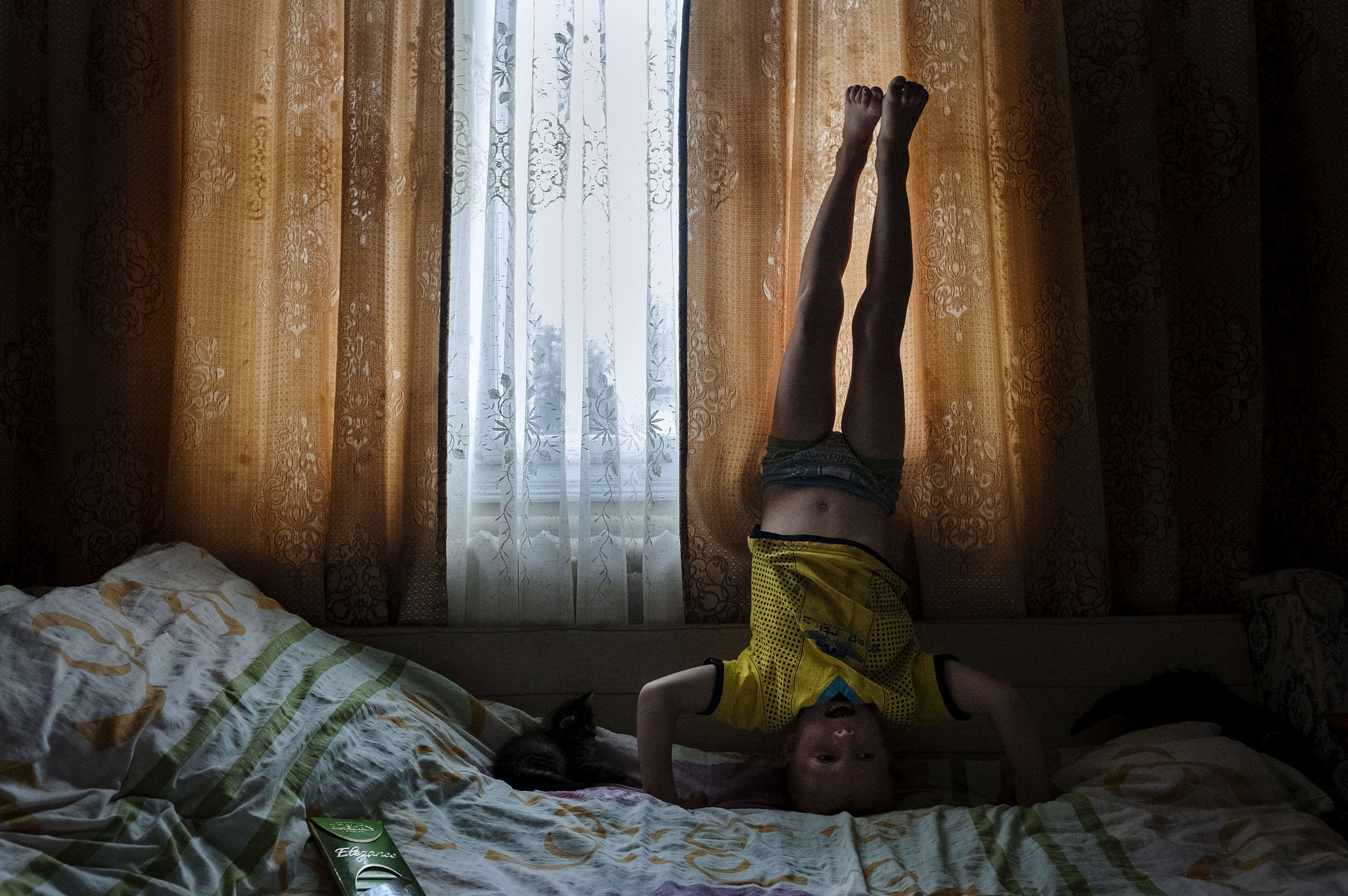 Stasic is bored and plays around the house before getting ready to go to church for a christening with his grandparents. He hasn’t seen his parents in real life for more than a year.