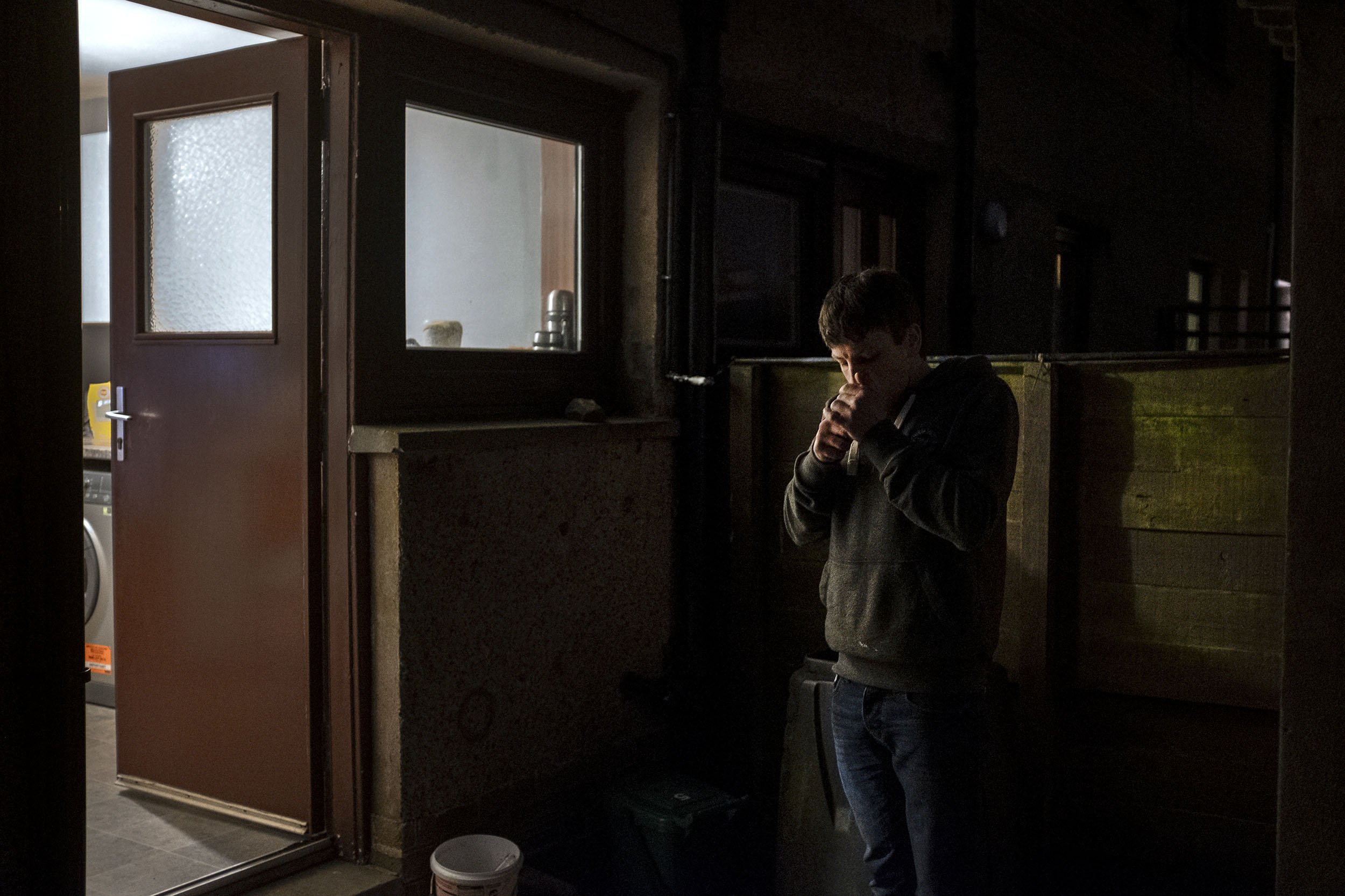 Nathan Milne lighting a cigarette by his back door. Nathan has a bairn on the way and is so scared for their future that he always tries to have enough food in his house to last him for at least a week, just incase chaos breaks out and the shops will