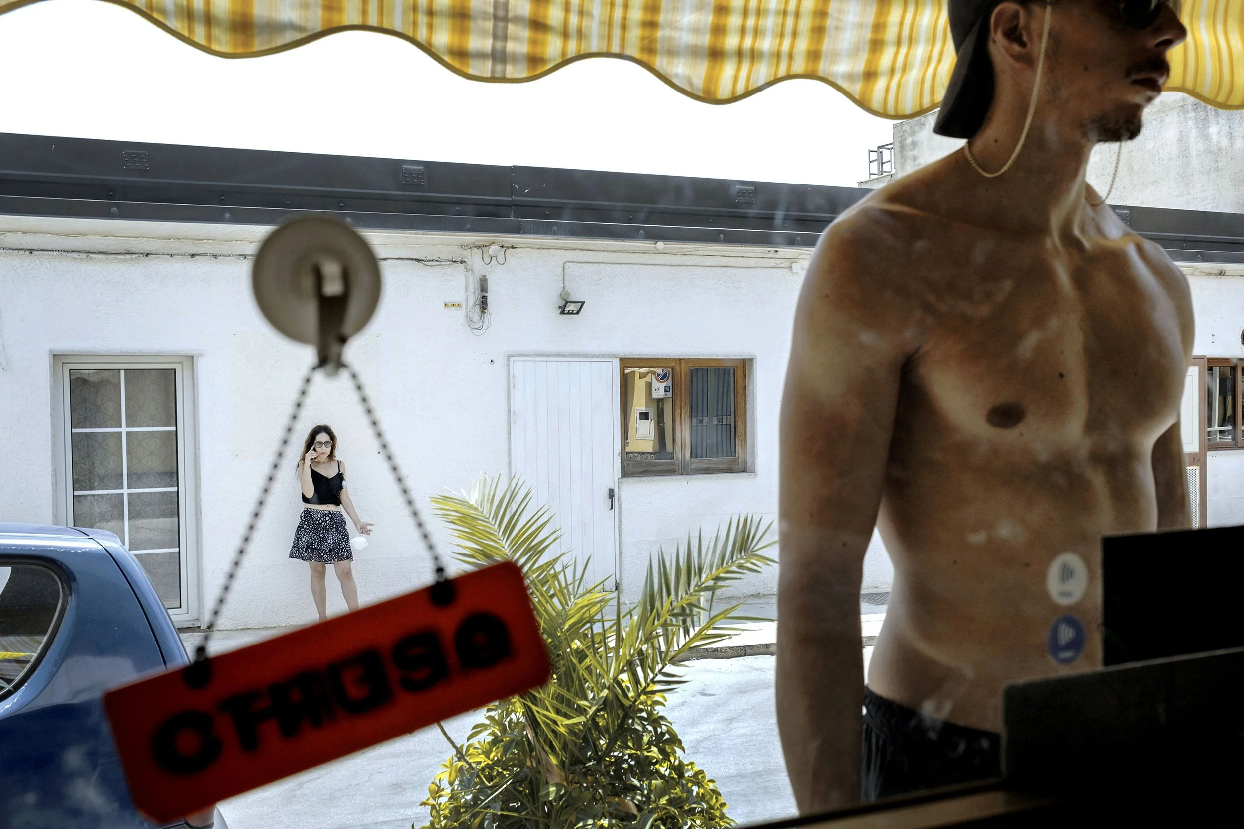 A man looks through a window into a shop in Marina di Modica, Sicily.