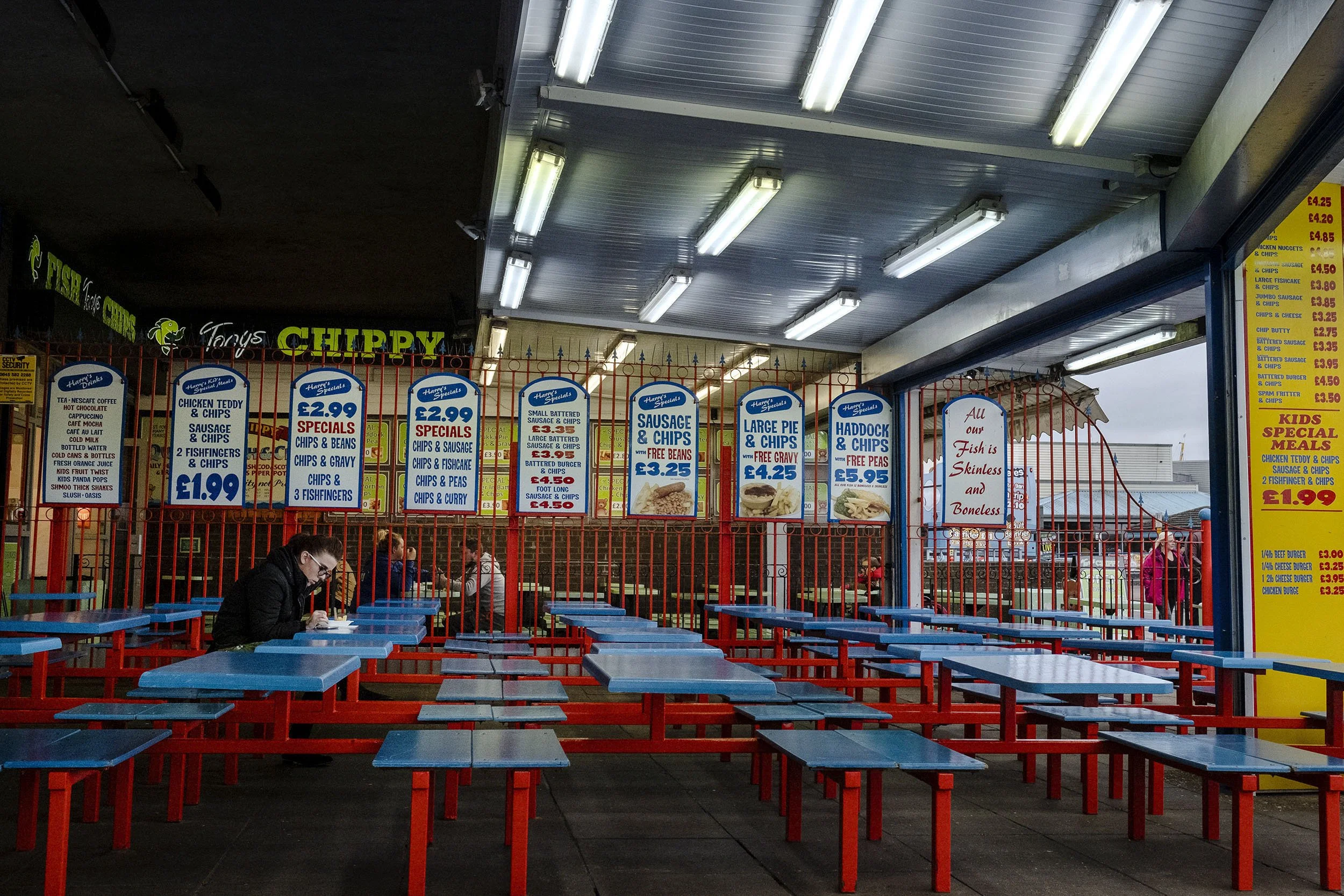 A lady eats her fish ’n’ chips at a seaside chippy. Skegness, England.
