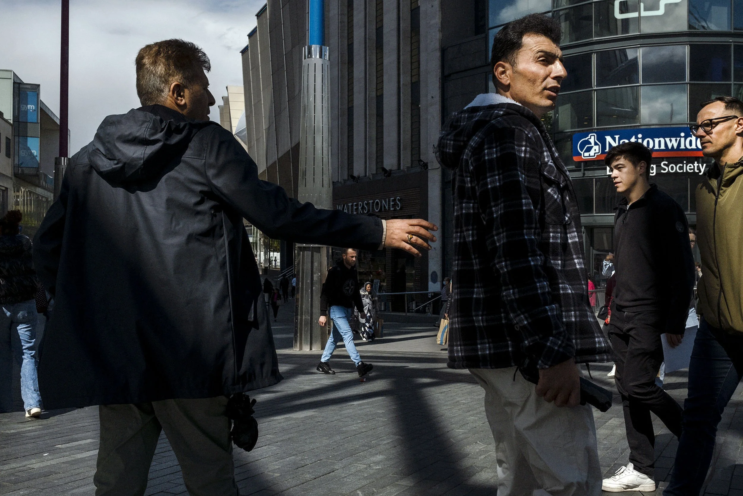 Men pass each other near the Bull Ring. Birmingham, England.