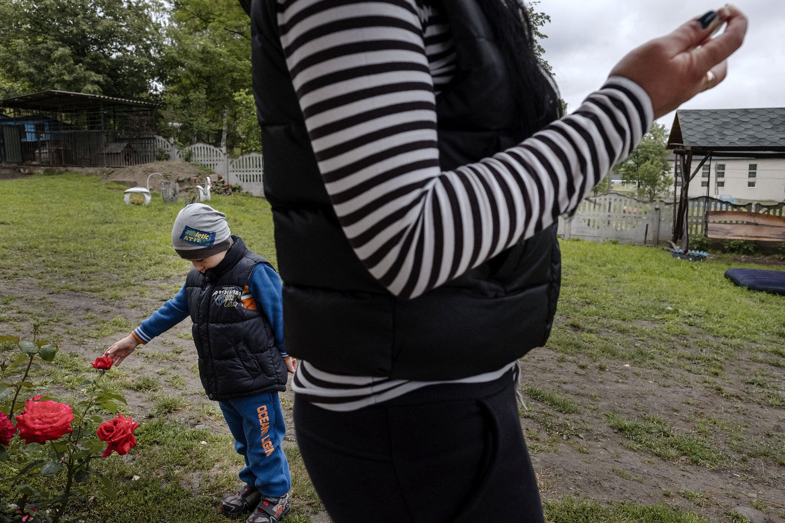 Vania’s son with his grandmother watch a wedding procession passing through the main street of Bobivtsi.