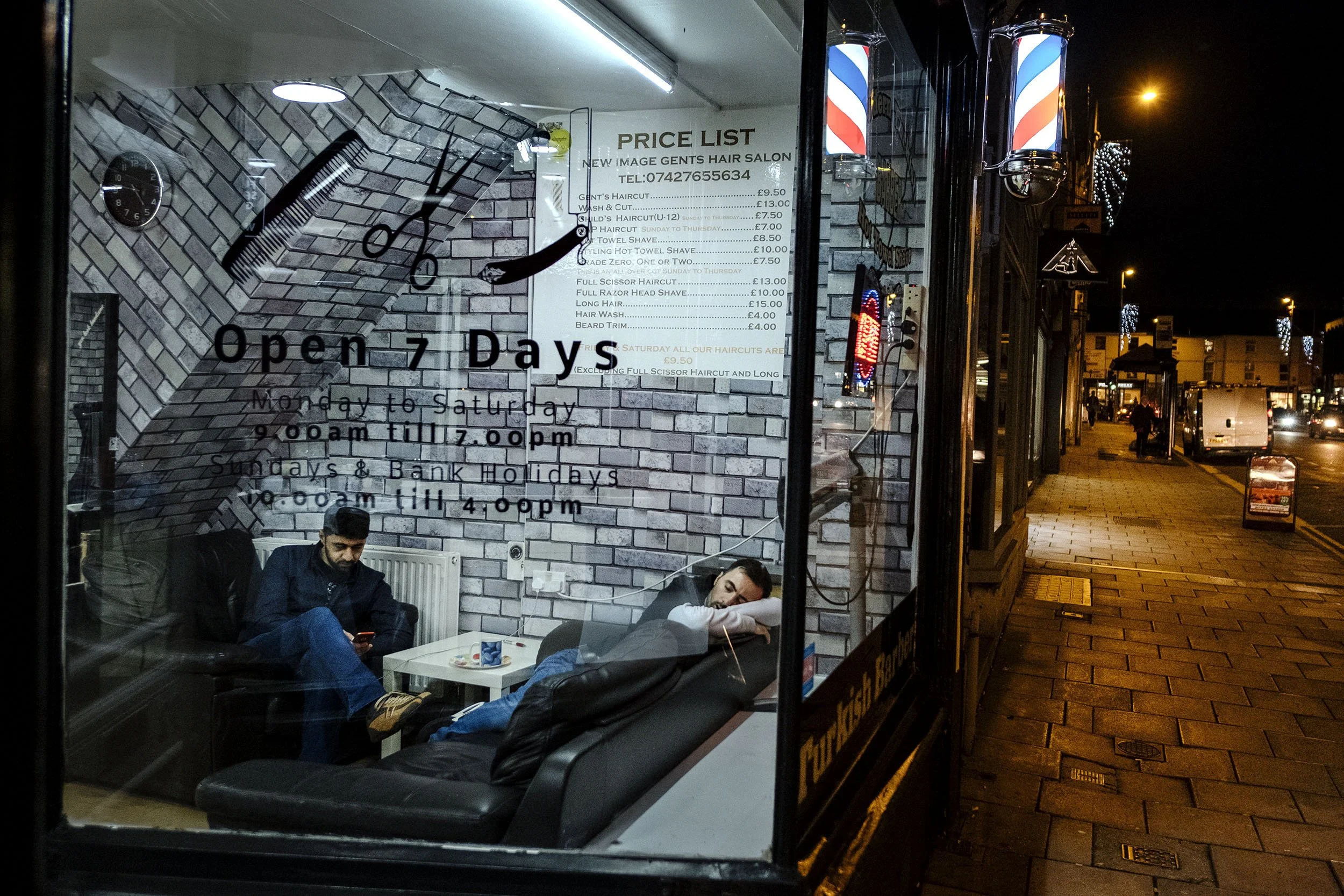Barbers waiting for customers, one fell asleep, up towards Old Town in Swindon, England.