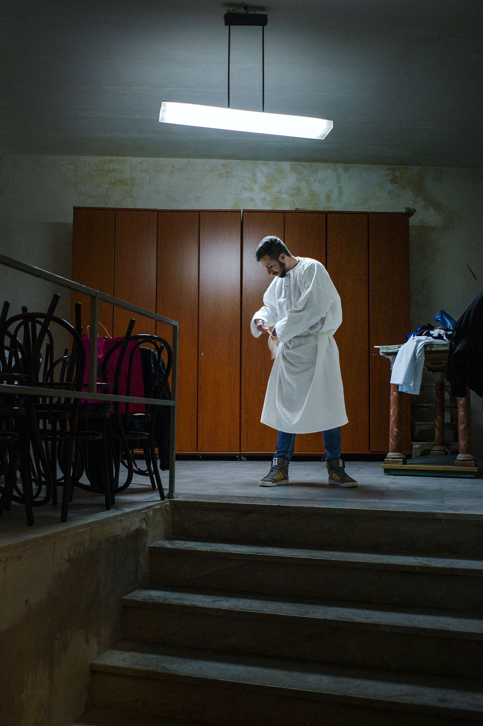 The day after the Good Friday procession a man prepares himself for the next procession in a back room at the San Nicolò Church in Randazzo, Sicily.