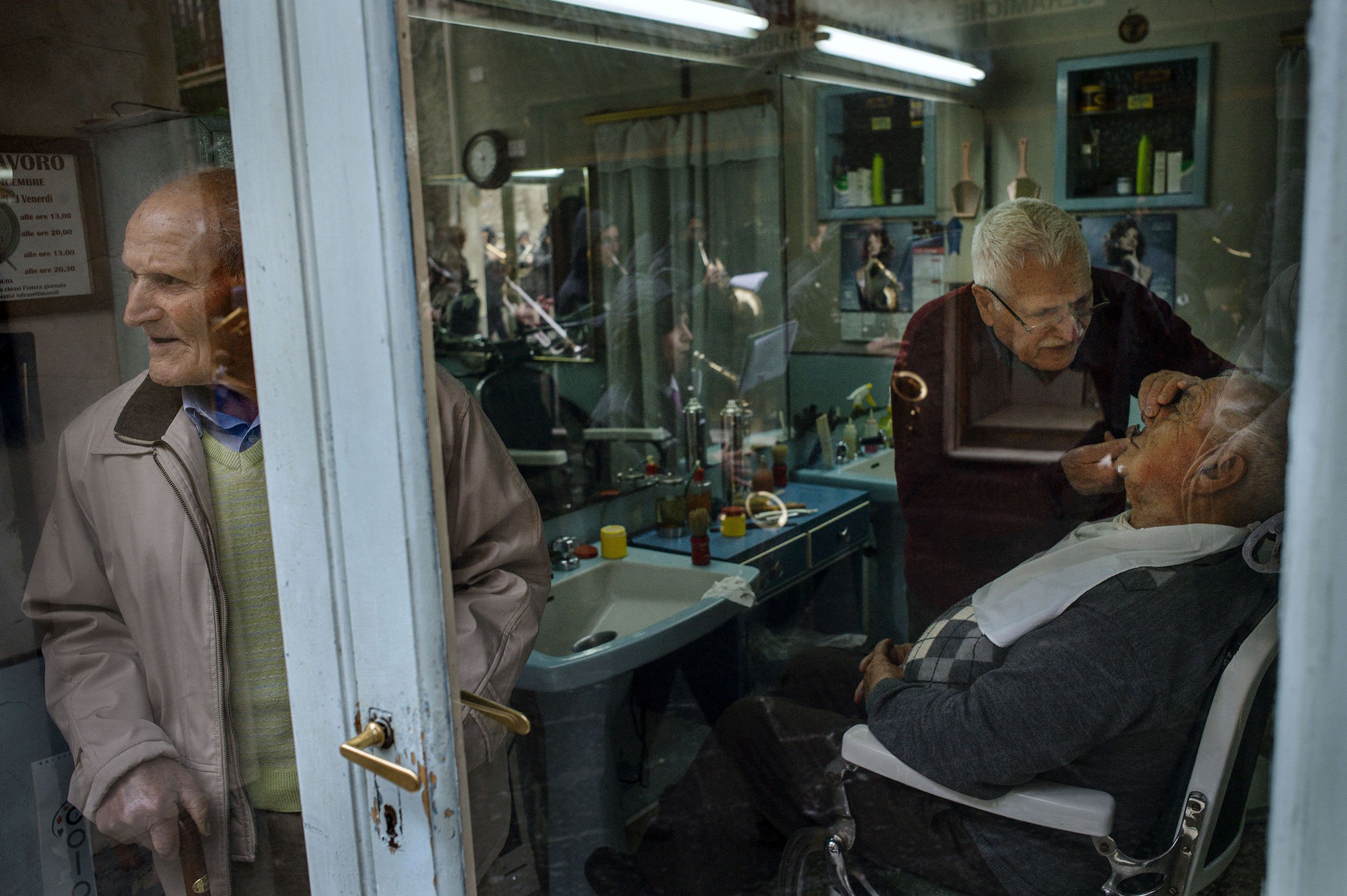 A man looks out of a barbershop window in Randazzo, Sicily.