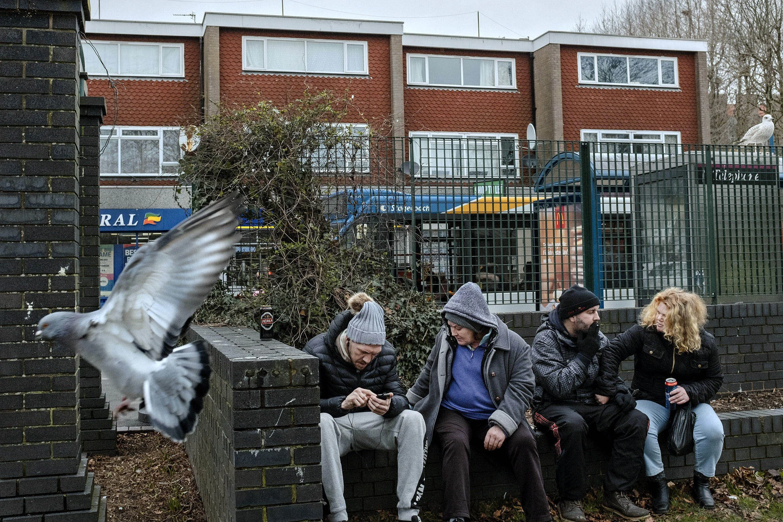 A group of day-drinkers sitting on a wall overlooking a park. Dover was badly effected by the Brexit and the port still struggles to manage the effect of not being part of the EU. Dover, England.
