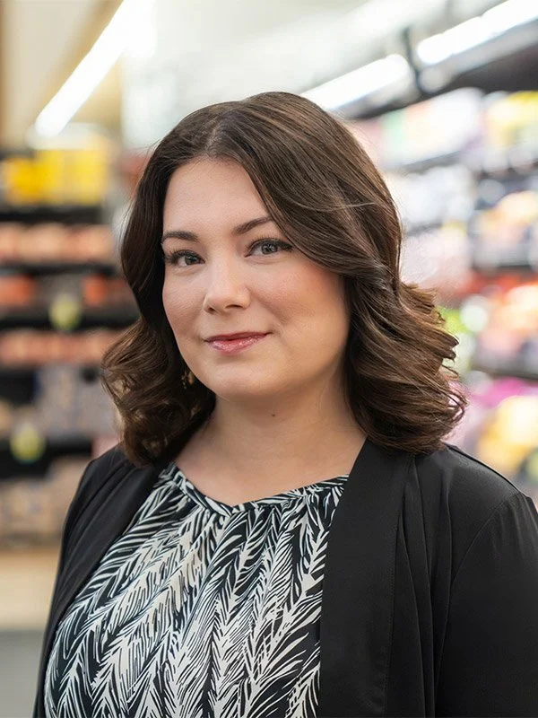 A woman with shoulder-length brown hair smiling in the best grocery store in Shasta Lake CA.