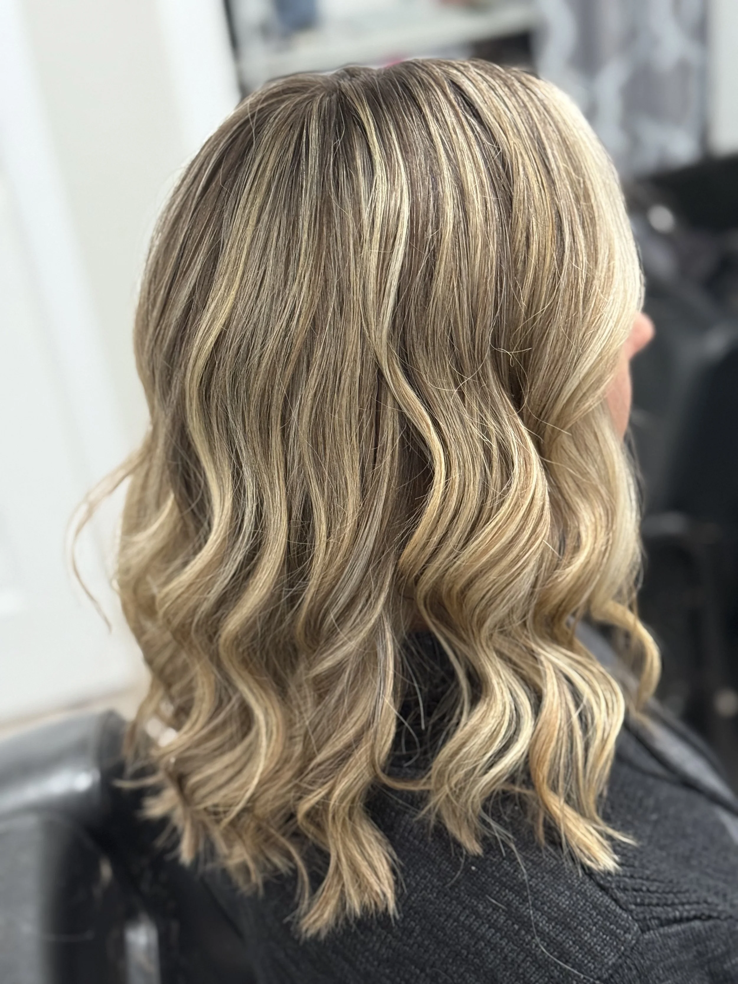 Side view of a woman with shoulder-length, wavy blonde hair.