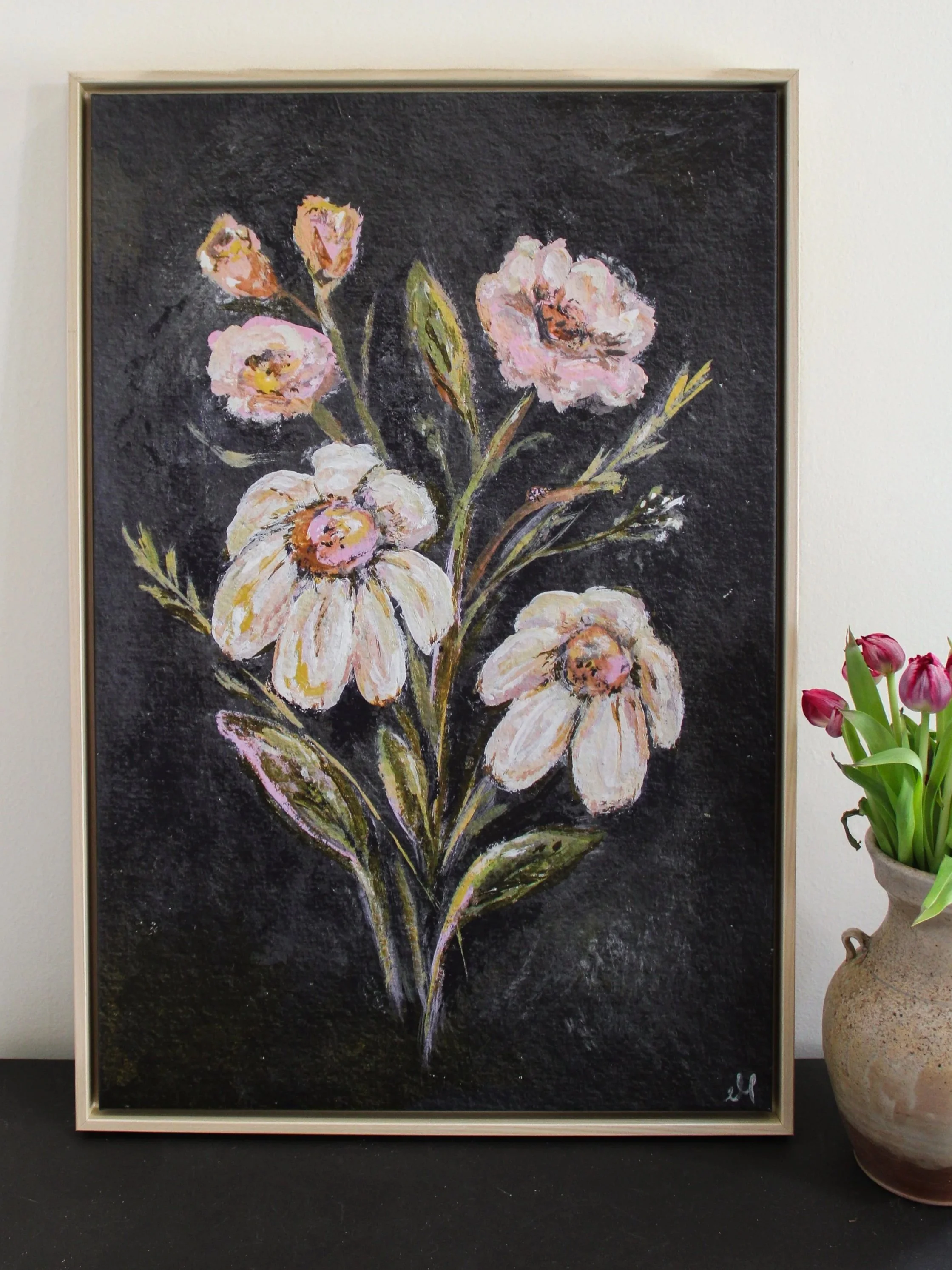 Painting of a bouquet of pink and peach flowers with green leaves on a dark background, framed in light-colored wood.