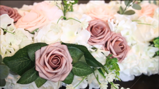 Arrangement of pink and white roses with green leaves.