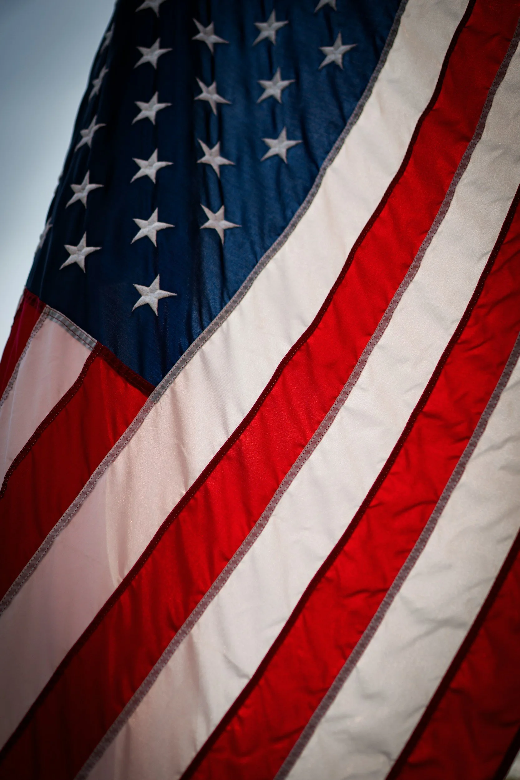 Close-up of an American flag, showing red and white stripes and a blue field with white stars.