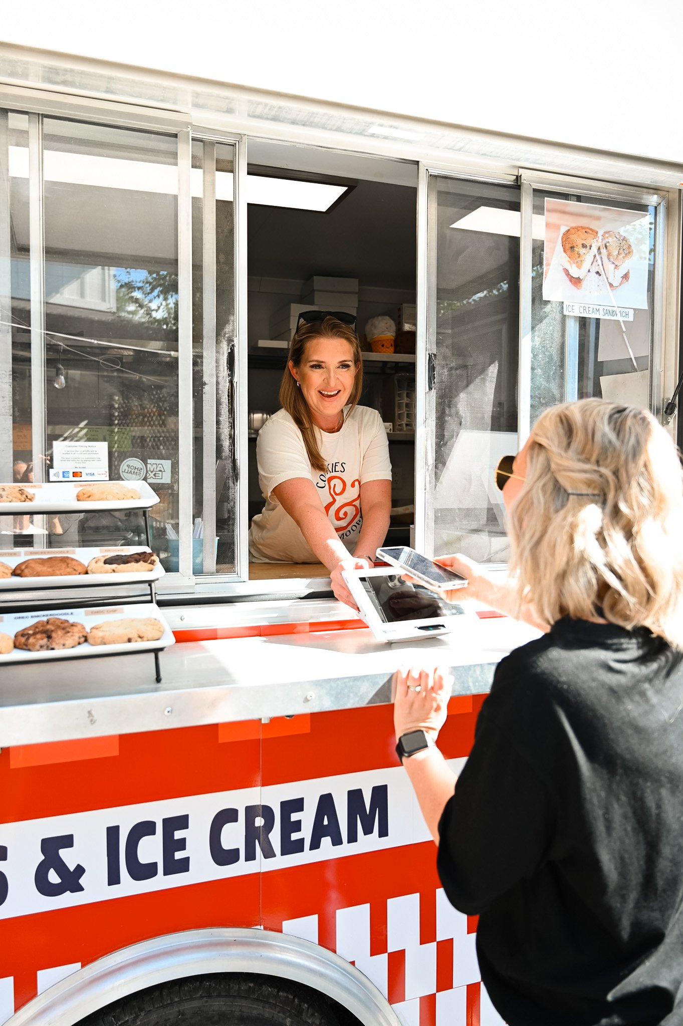 A woman is buying ice cream or cookies from the Cookies & Moore Food Truck at Red's Corner in Southern Pines, North Carolina.