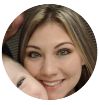 Close-up of a smiling woman with blonde hair and blue eyes, partially holding a child.