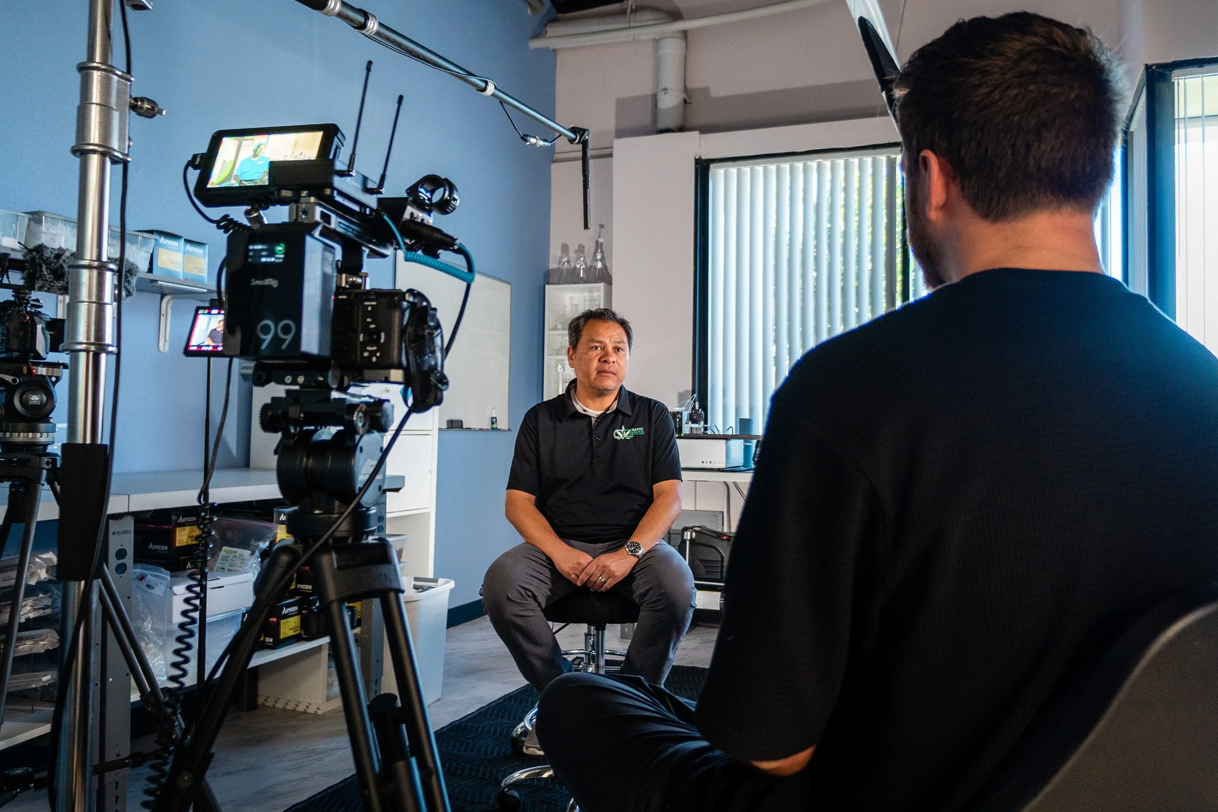 A man being interviewed on camera in a room with equipment and a whiteboard by a san diego video production company