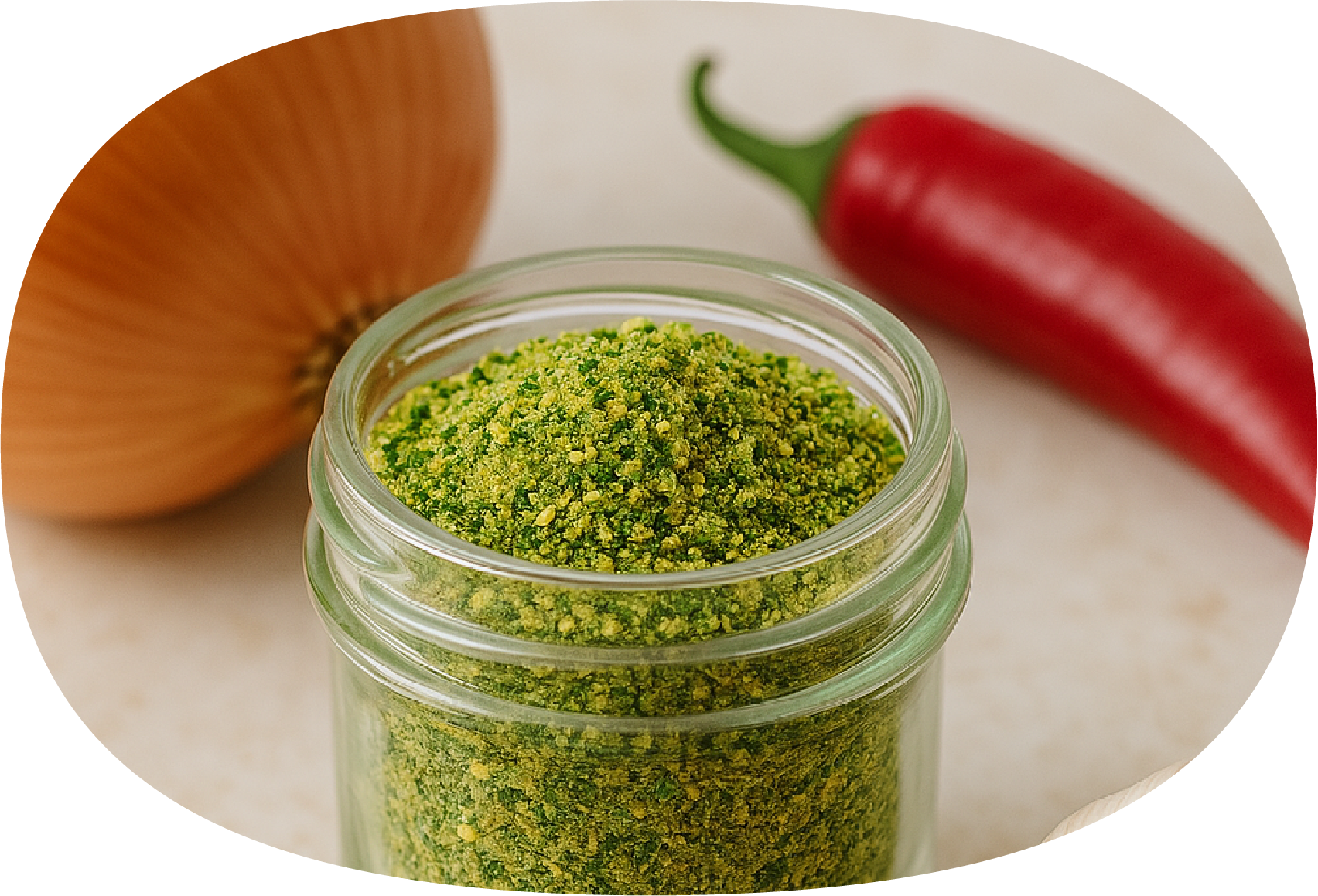Pote de pó de color verde ao centro, ao fundo cebola e uma pimenta vermelha