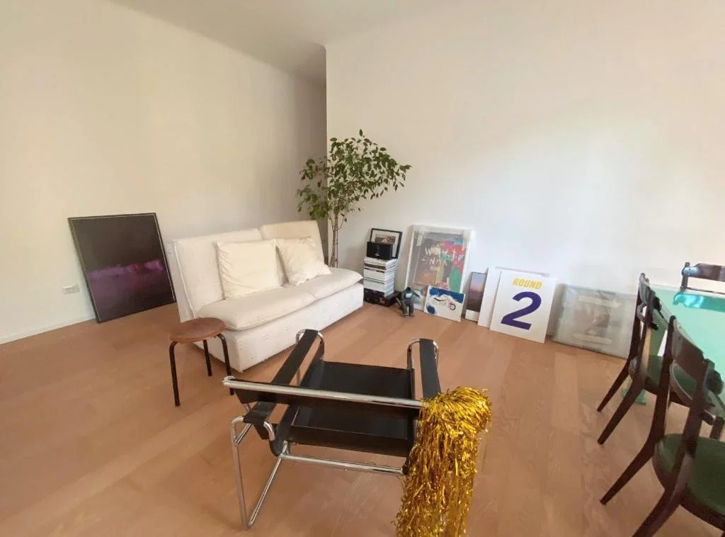 Soggiorno con divano bianco, poltrona nera con braccioli d'argento, tavolo con cartelli di vittoria e altri oggetti di decorazione.