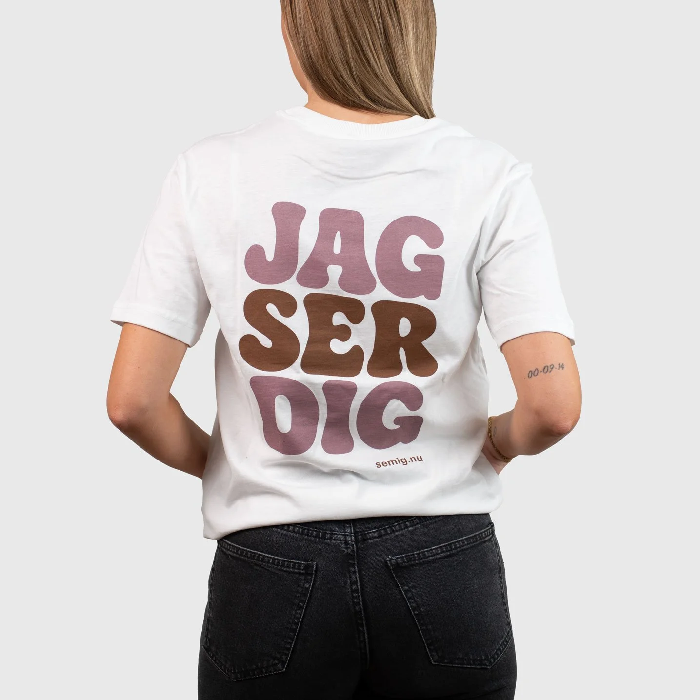 Kvinna i vit oversize t-shirt bakifrån med trycket ”Jag ser dig”