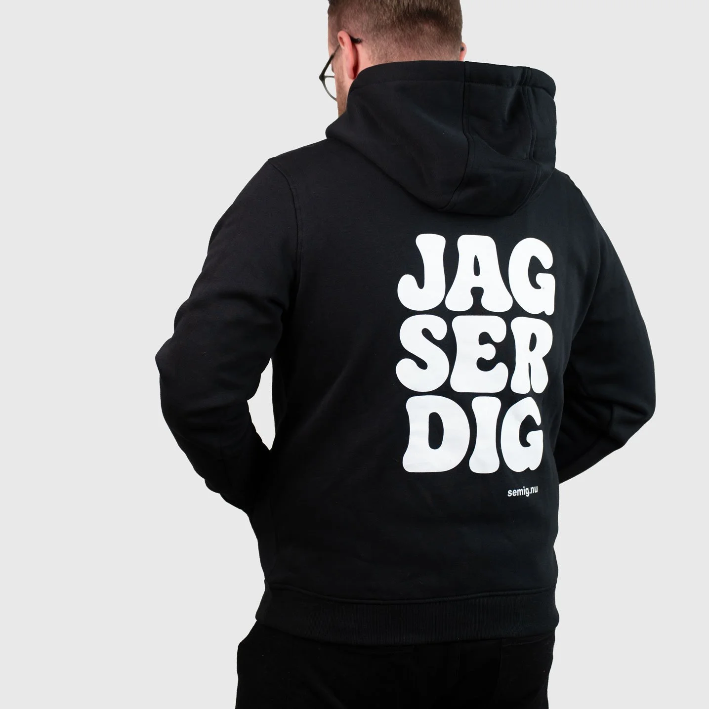 Man i svart hoodie bakifrån med tryck ”Jag ser dig”