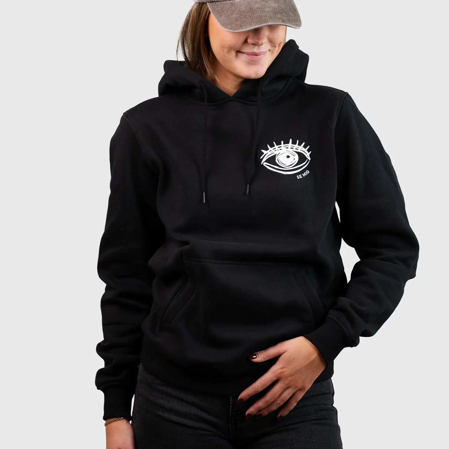 Kvinna i keps och svart hoodie med ögonlogga på bröstet