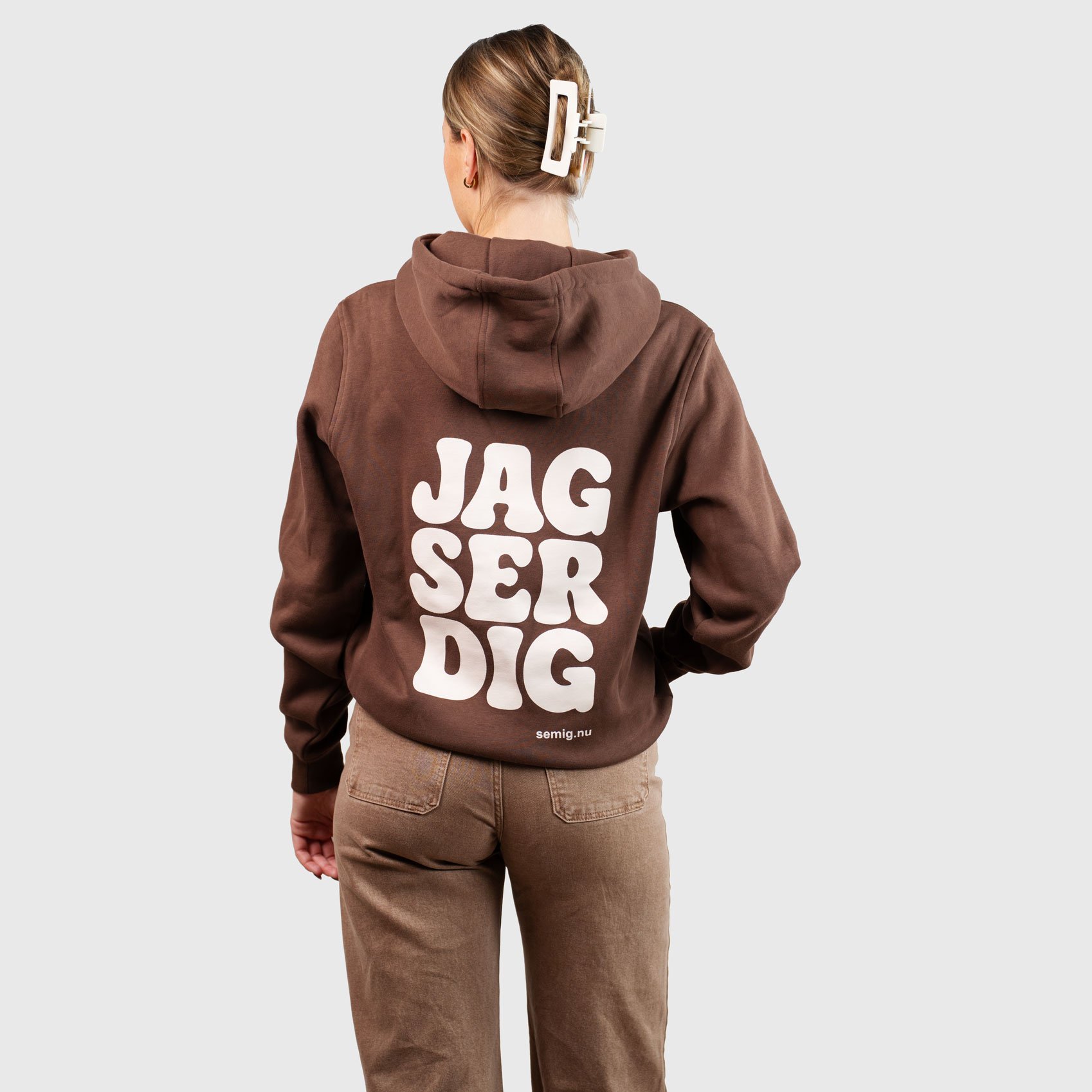 Kvinna i brun hoodie bakifrån med trycket ”Jag ser dig”