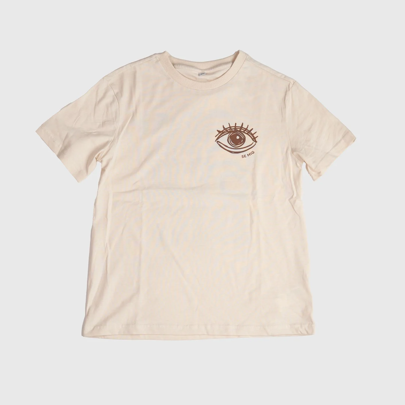 Sandfärgad oversize t-shirt i tjejmodell framifrån med liten ögonlogga