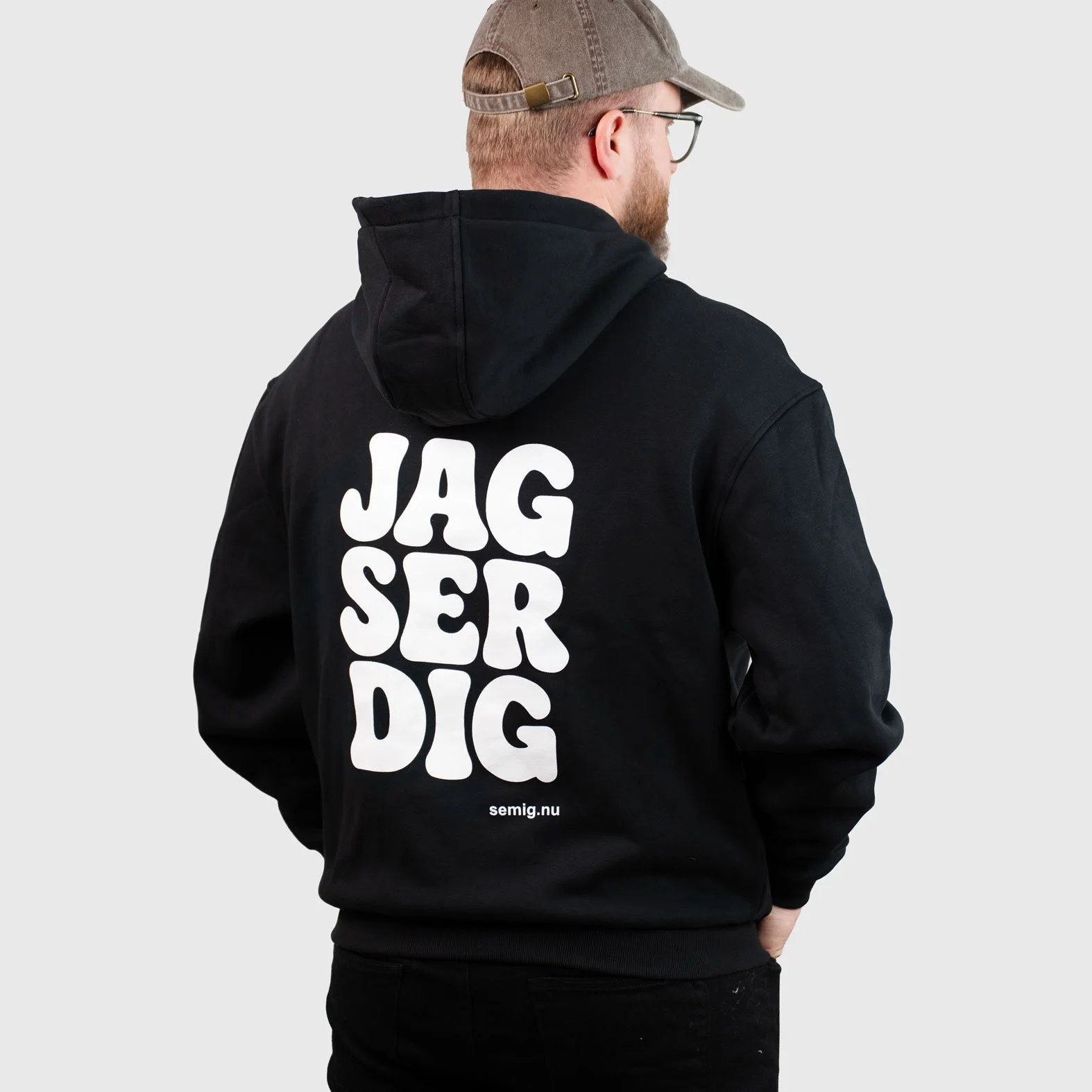 Man i svart zip-hoodie bakifrån med tryck ”Jag ser dig”
