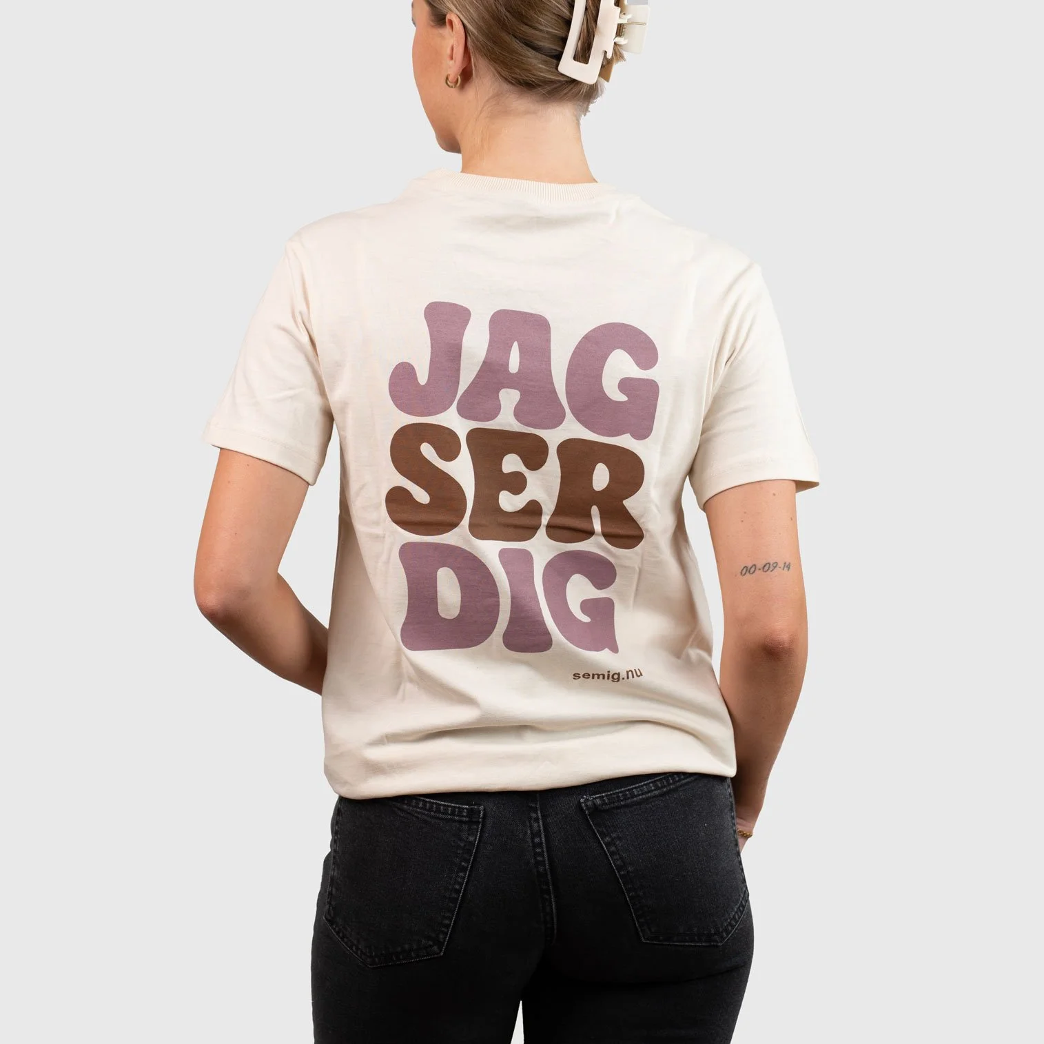 Kvinna i sandfärgad oversize t-shirt bakifrån med trycket ”Jag ser dig”