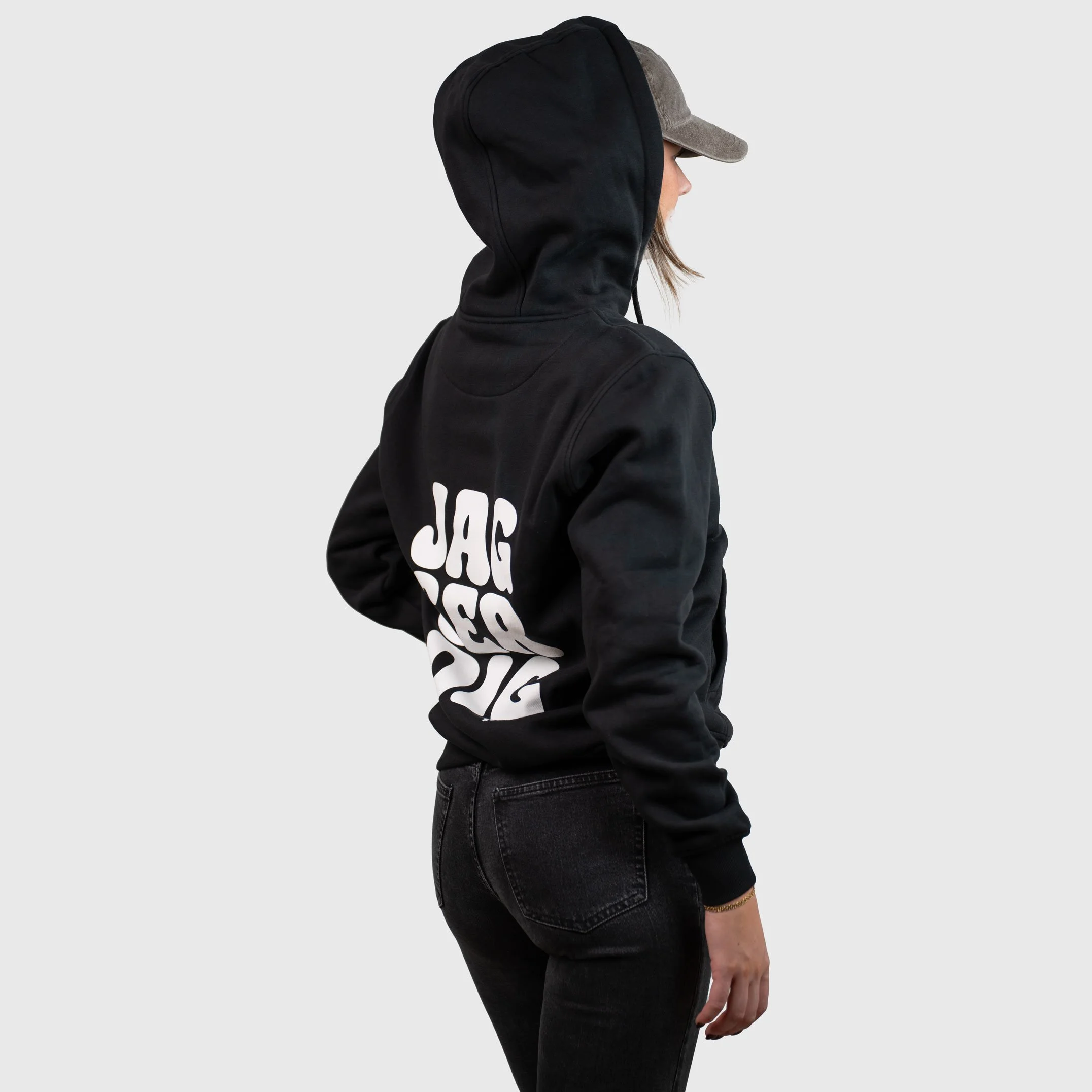 Kvinna i svart hoodie från sidan med trycket ”Jag ser dig” på ryggen
